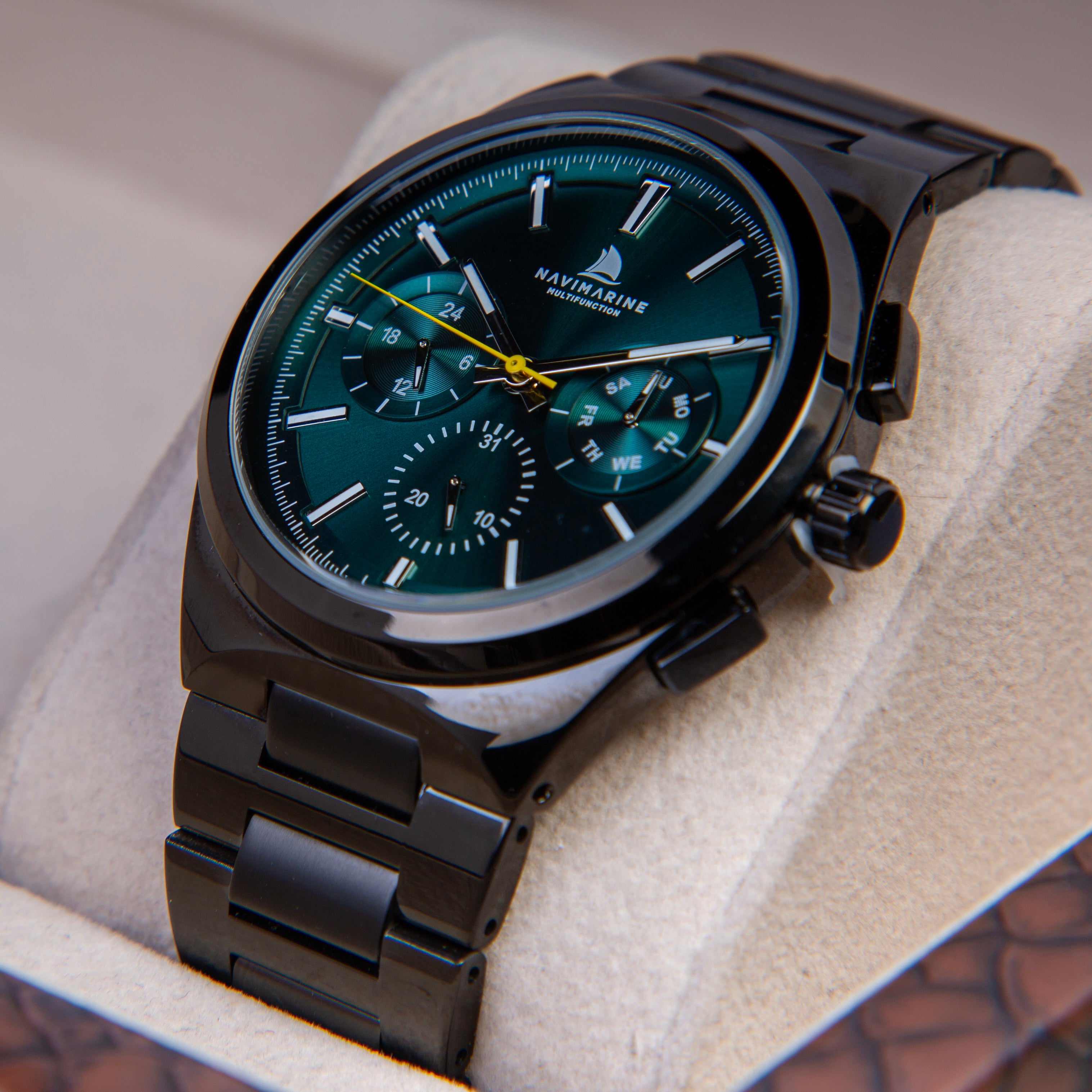 Black wristwatch with a green dial on a soft surface