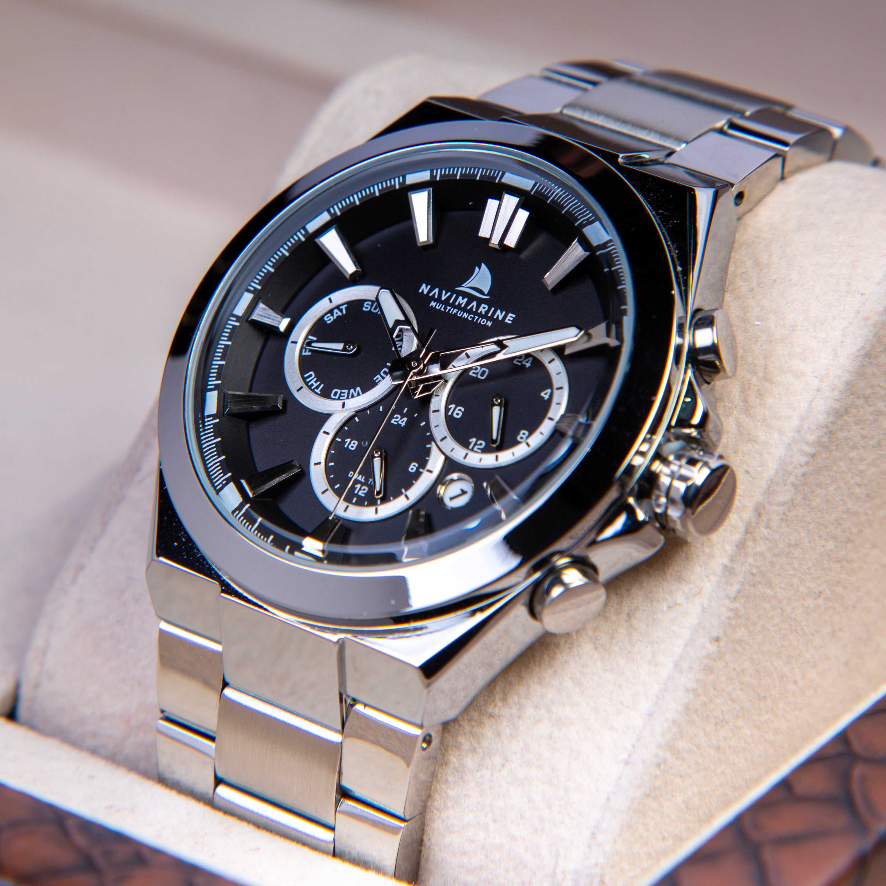 Silver wristwatch with black face on a textured surface
