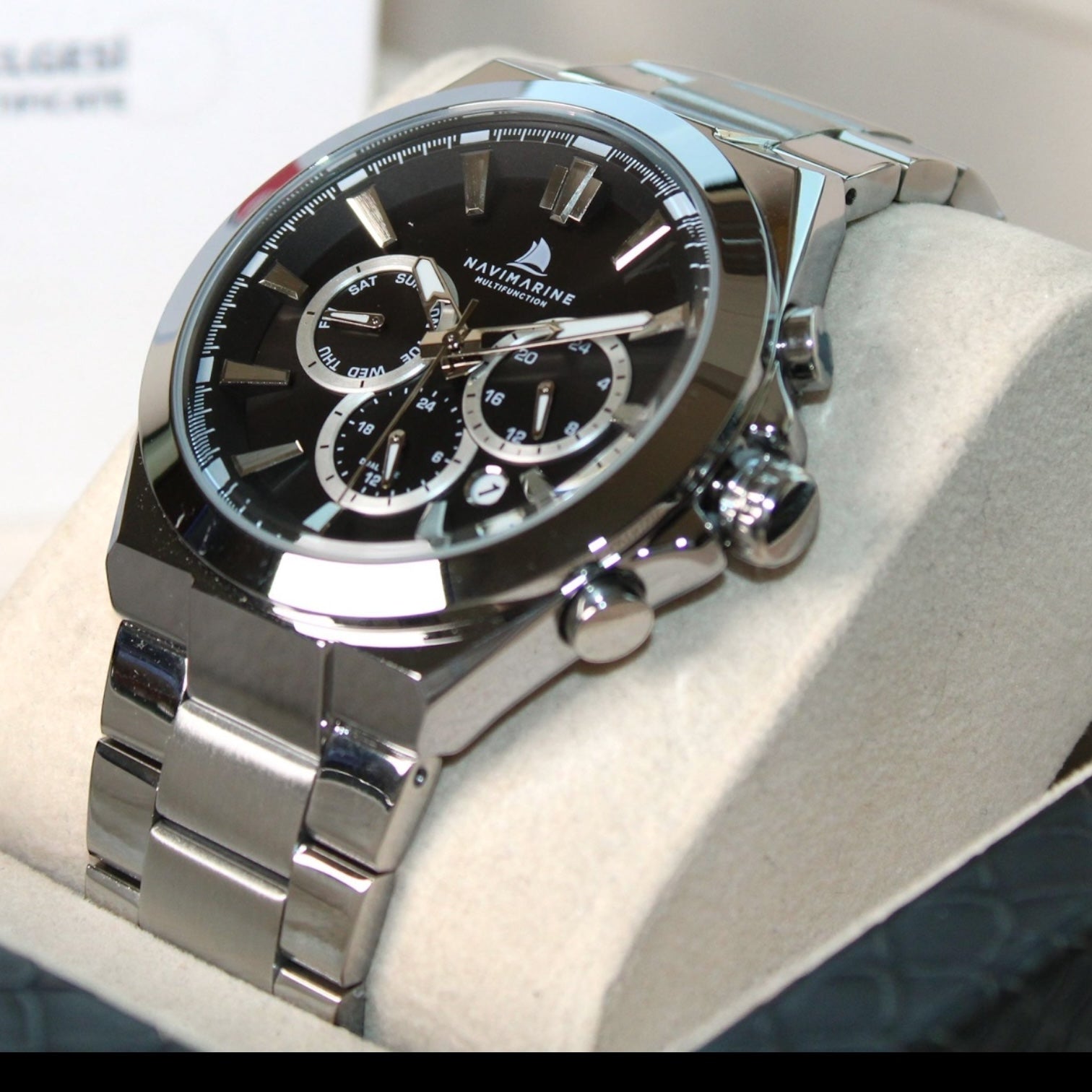 Silver watch with black face on a white cushion
