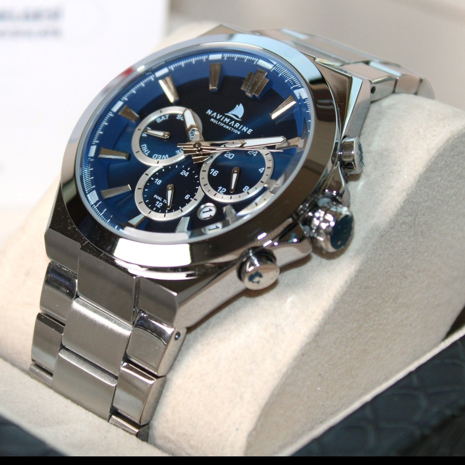 Silver watch with blue face on a white cushion