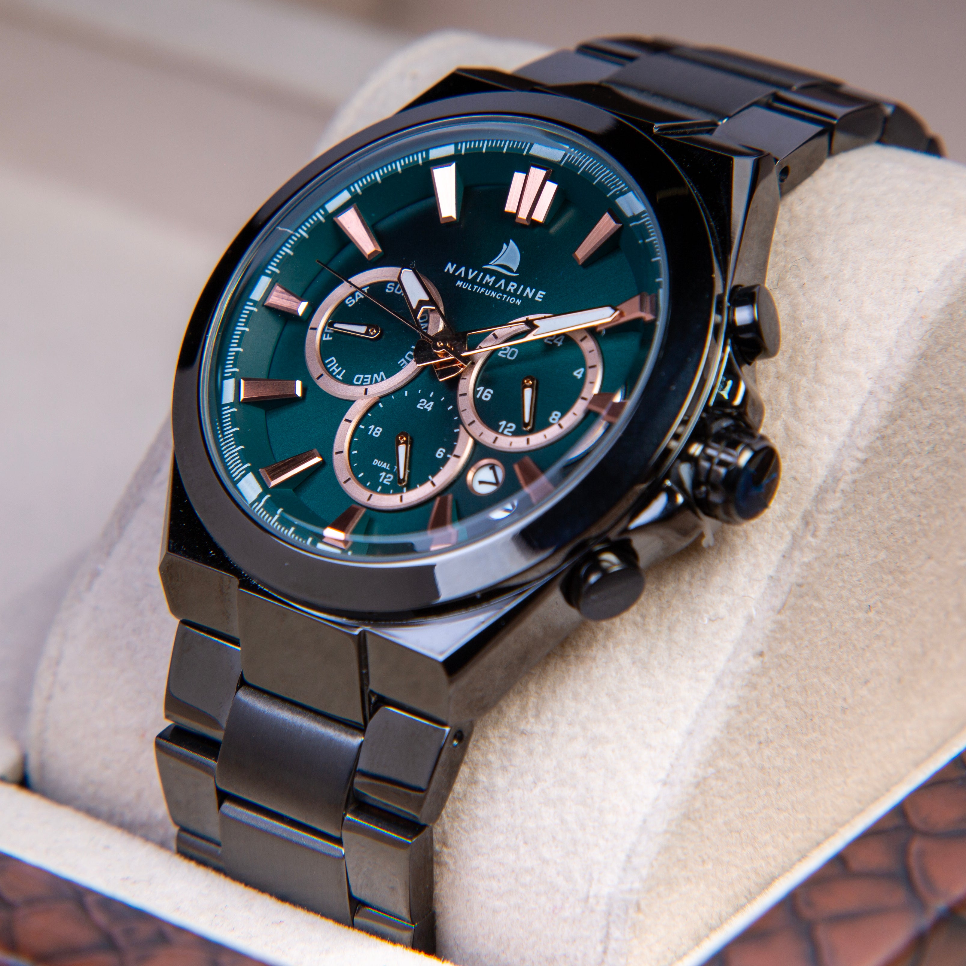 Luxury watch with black strap and green dial on a soft surface