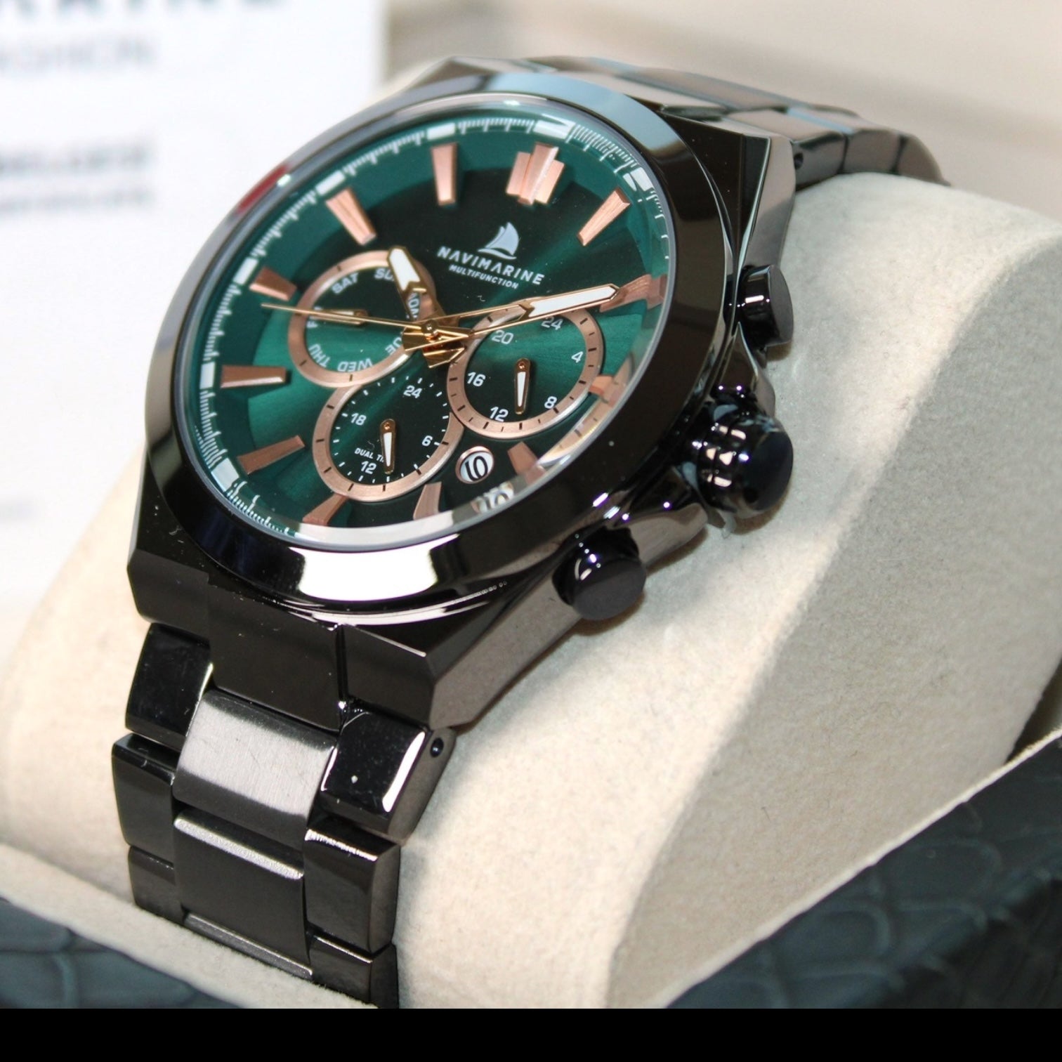 Luxury watch with a green face and black strap on a white cushion