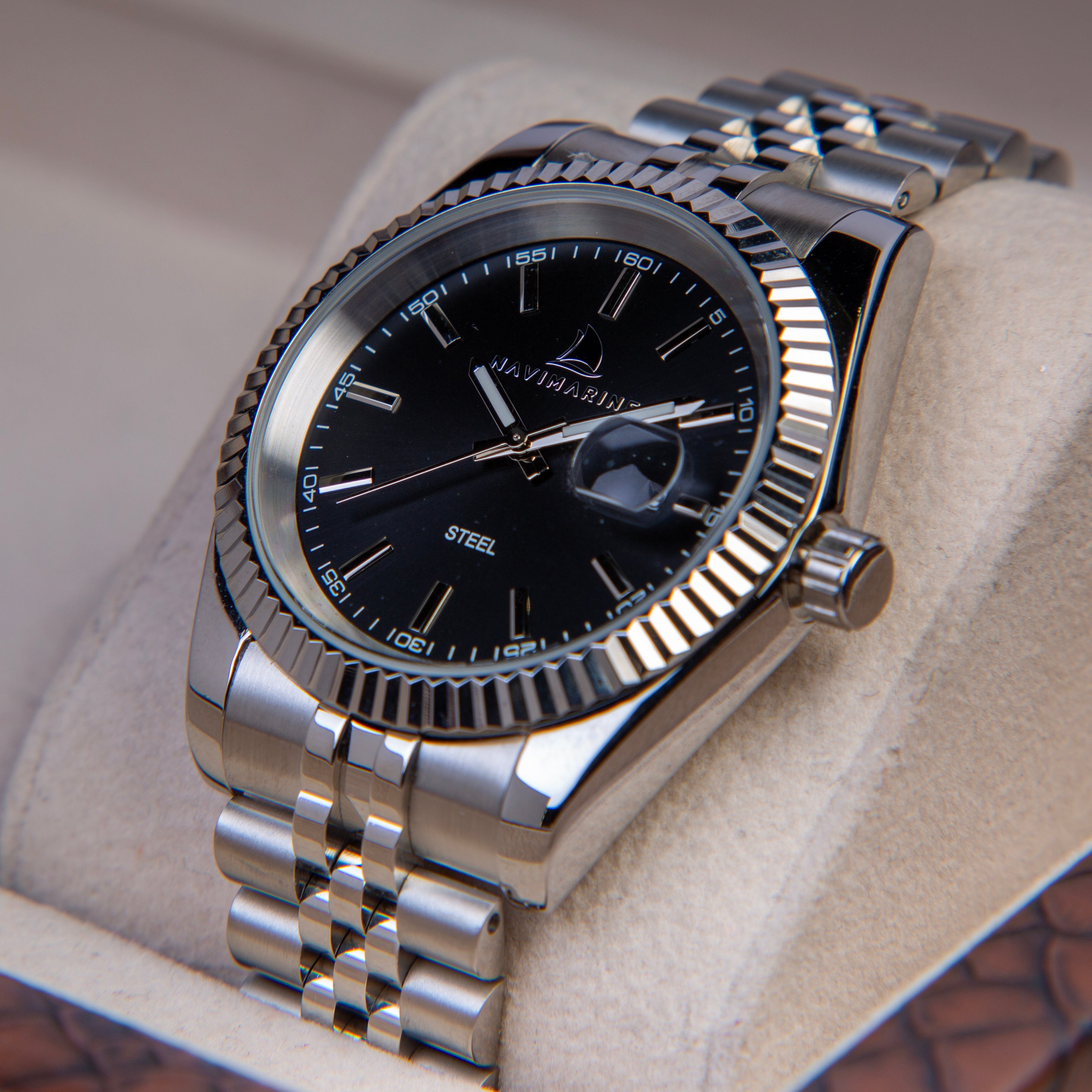 Silver watch with black dial on a beige cushion