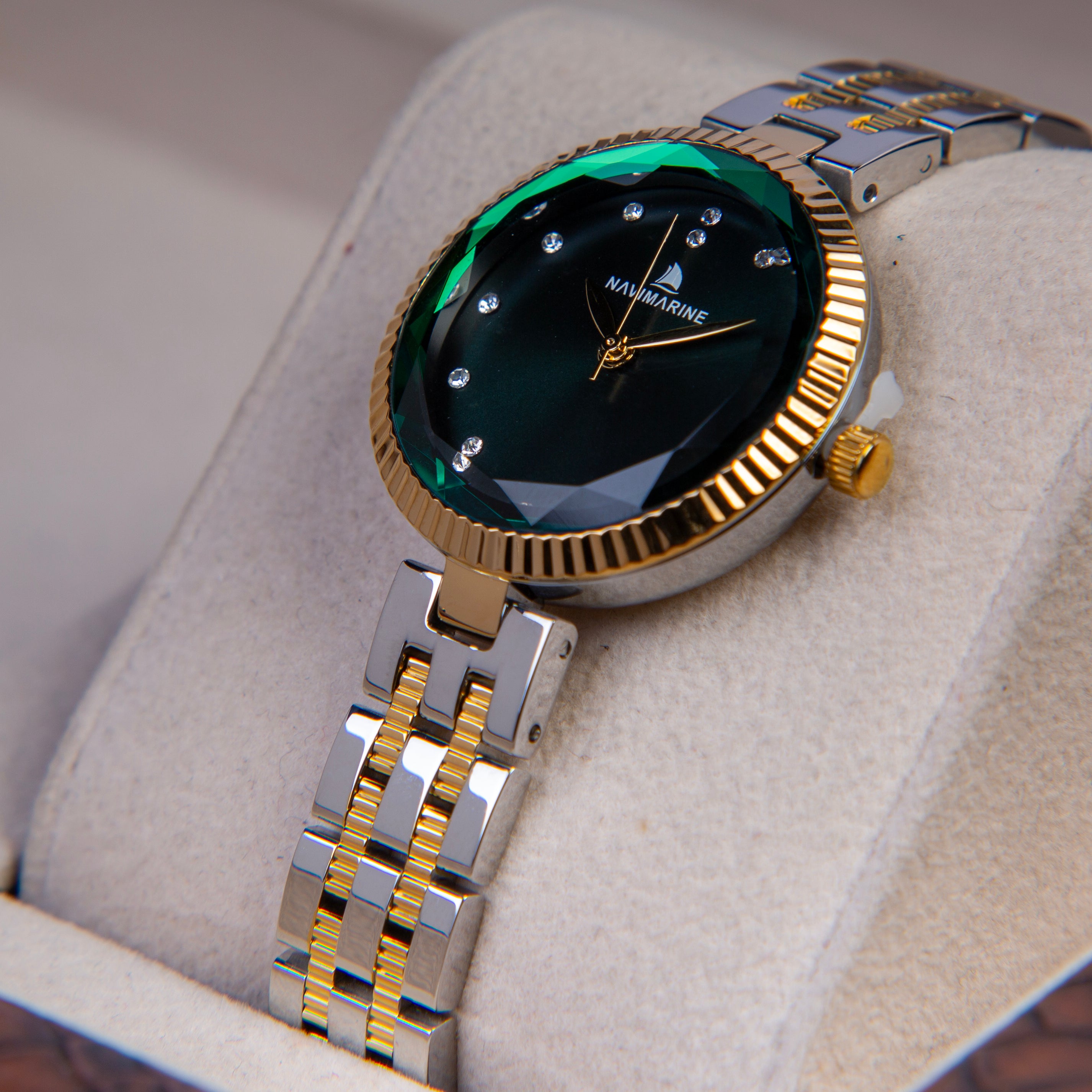 Luxury watch with green face and gold accents on a light gray background