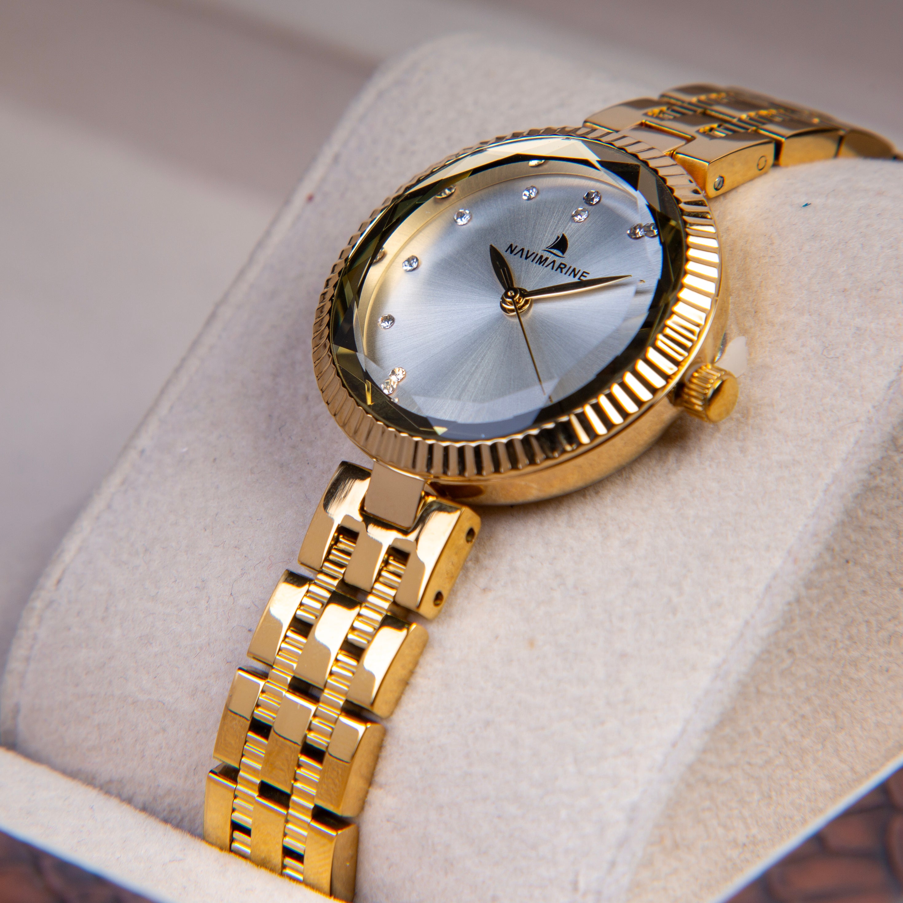 Gold wristwatch with a silver face on a light gray cushion