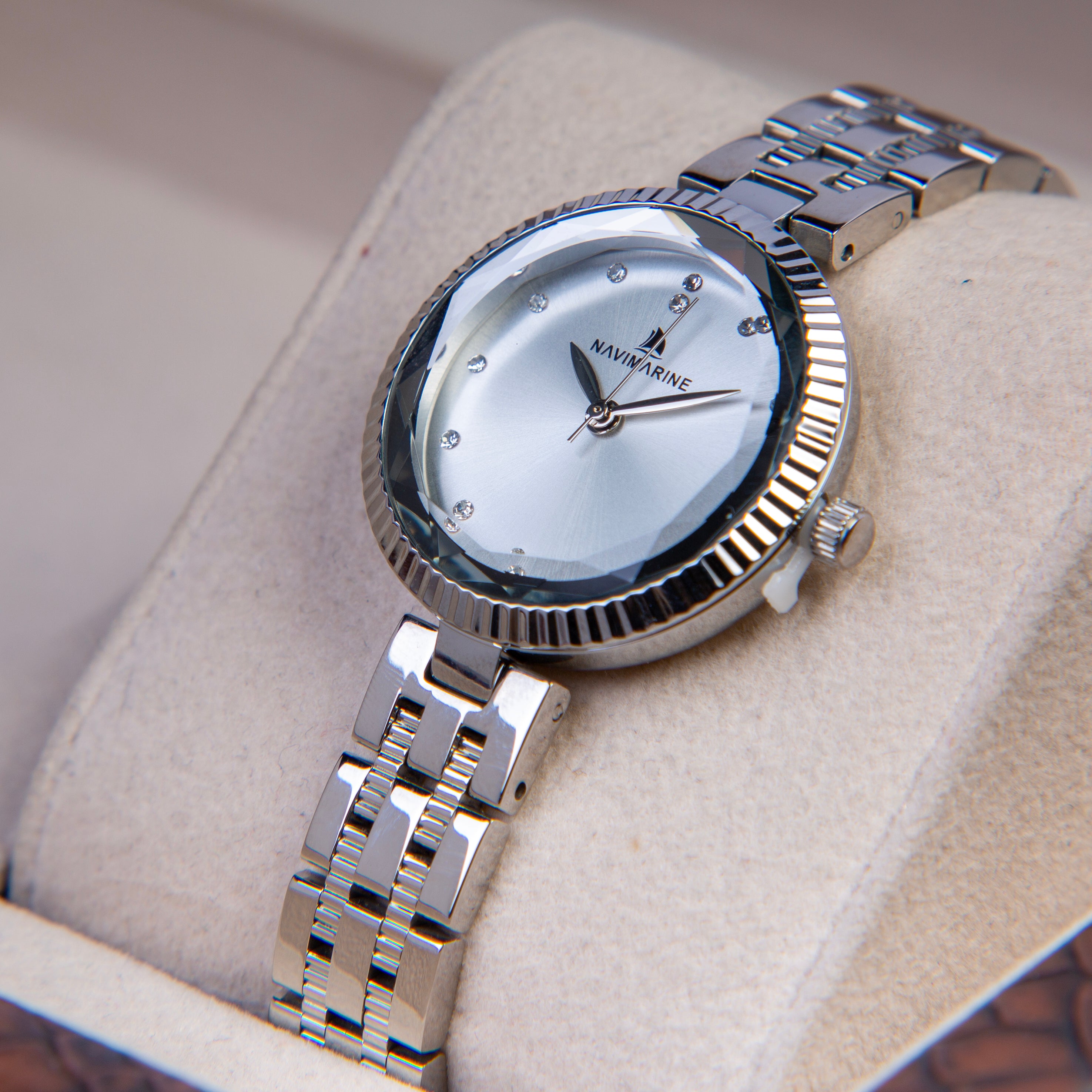 Silver wristwatch with a white face on a beige cushion