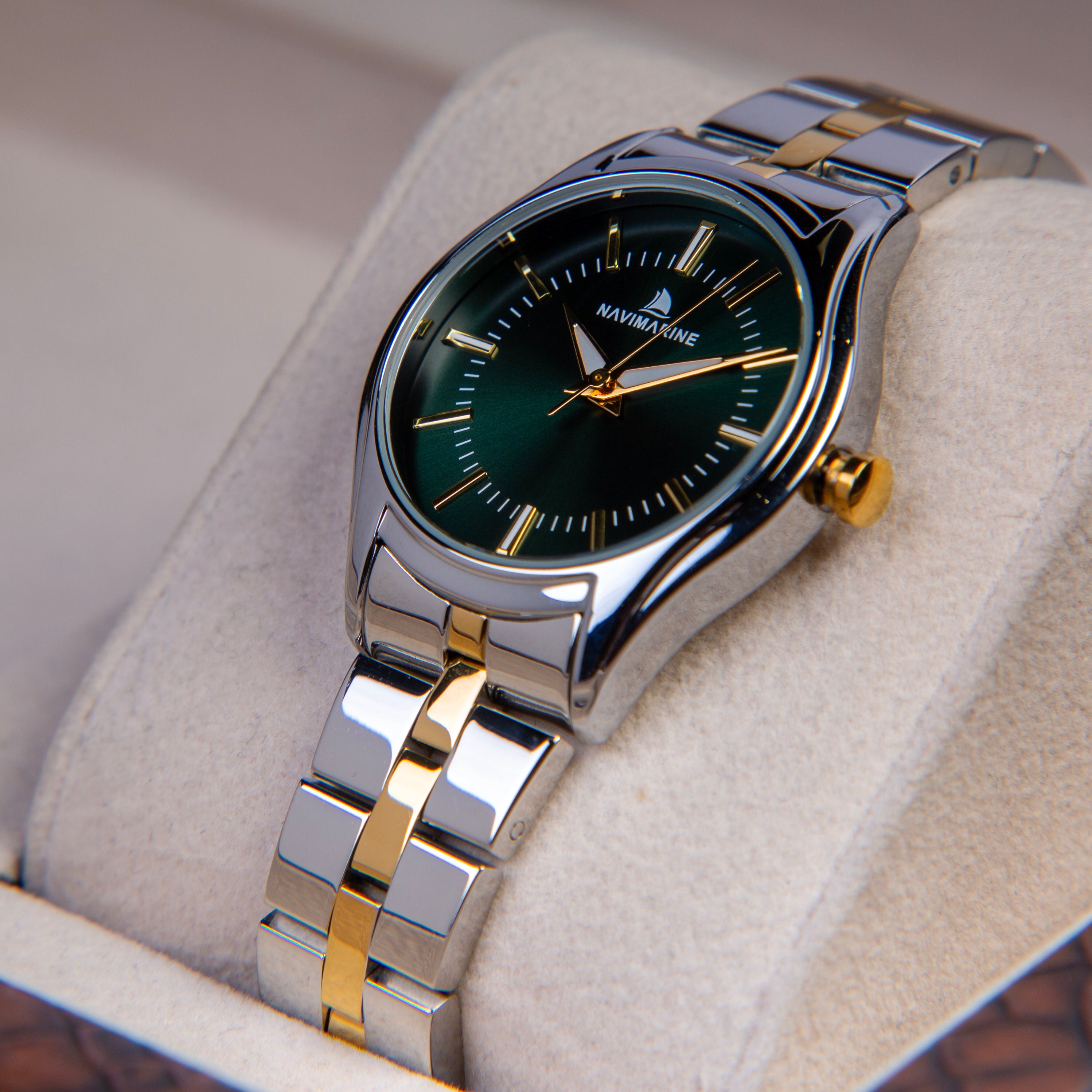 Silver and gold watch with green dial on a soft surface