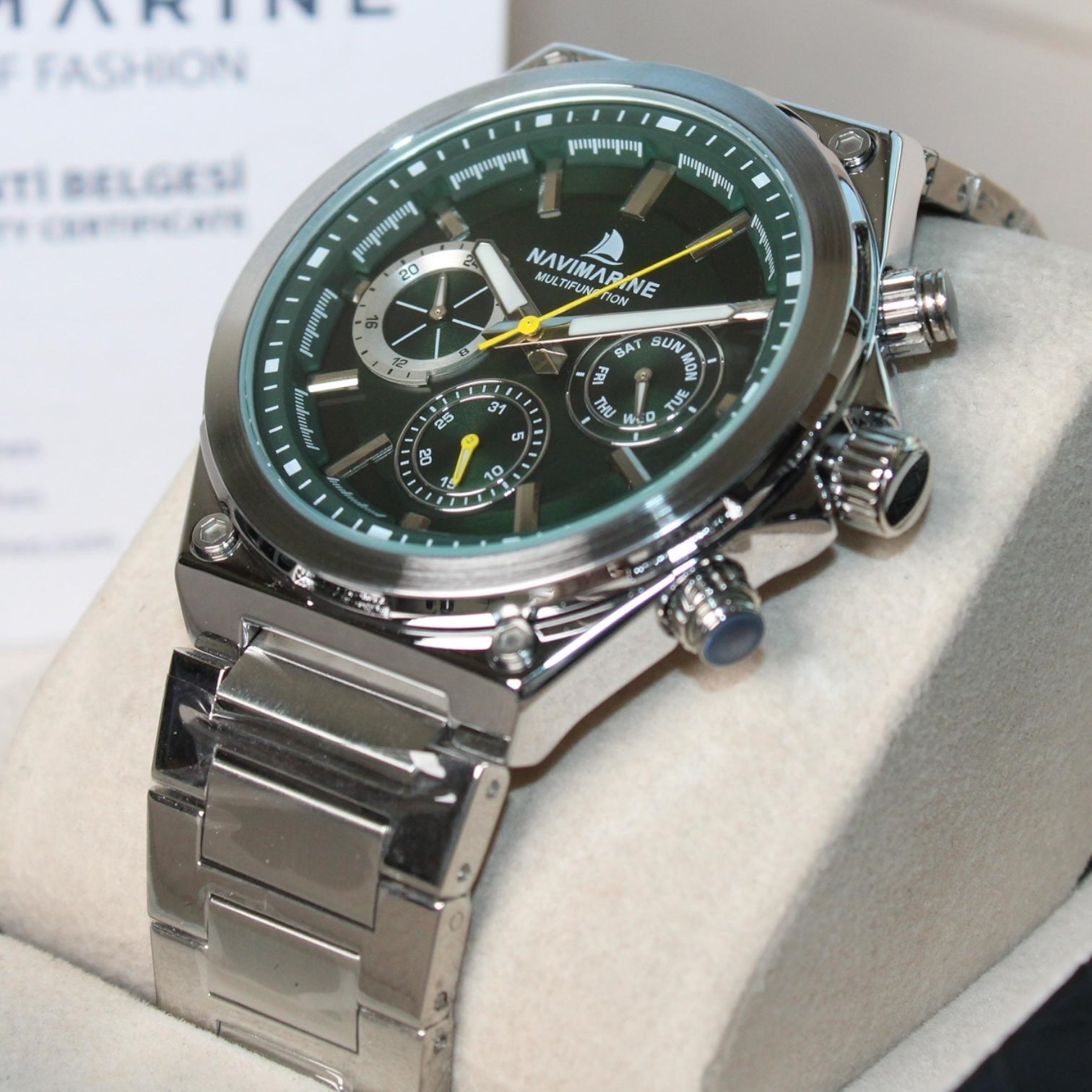 Silver watch with a green face on a white surface