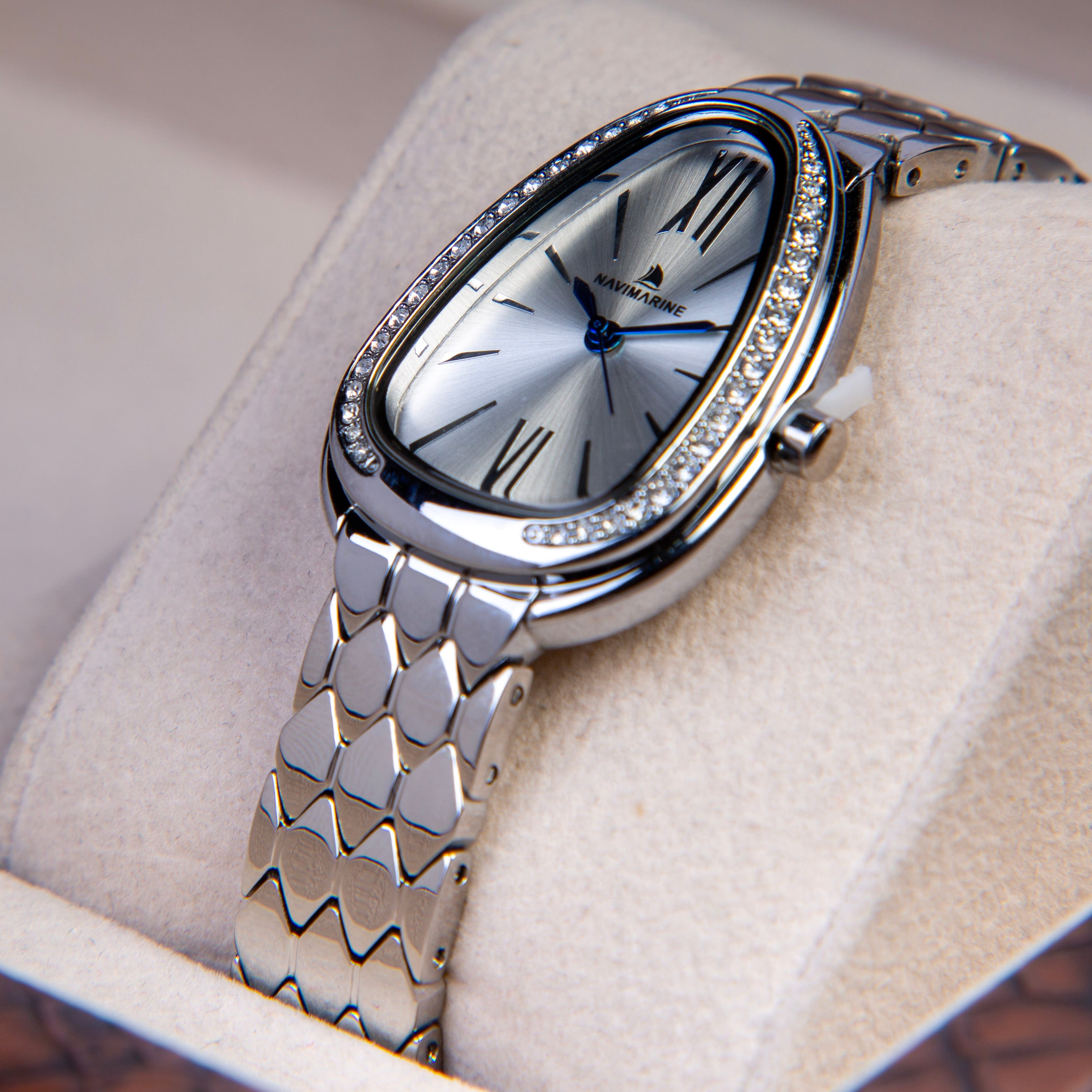 Silver wristwatch with decorative band on a beige cushion