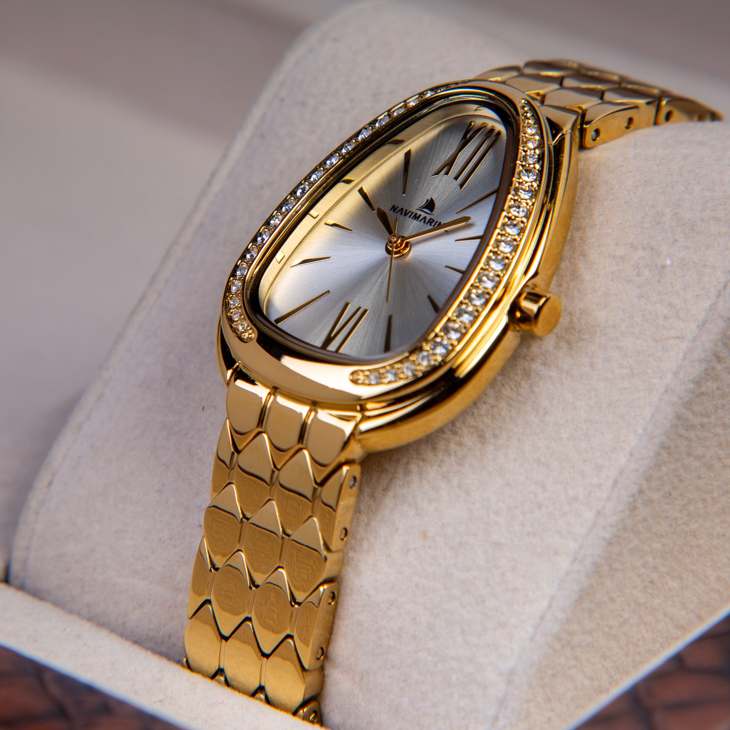 Gold wristwatch with diamond-studded bezel on a light gray cushion