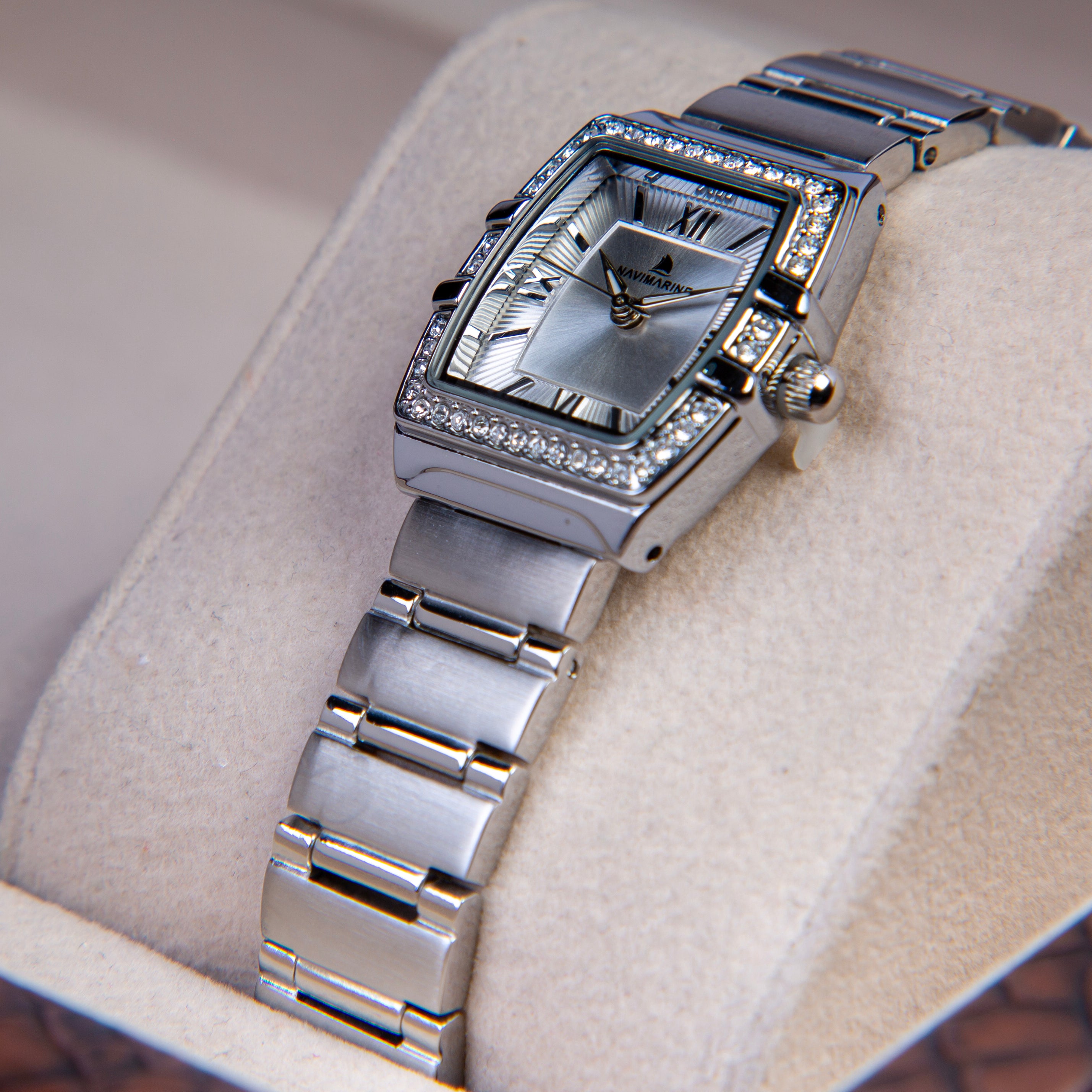 Silver wristwatch with diamond accents on a light fabric background