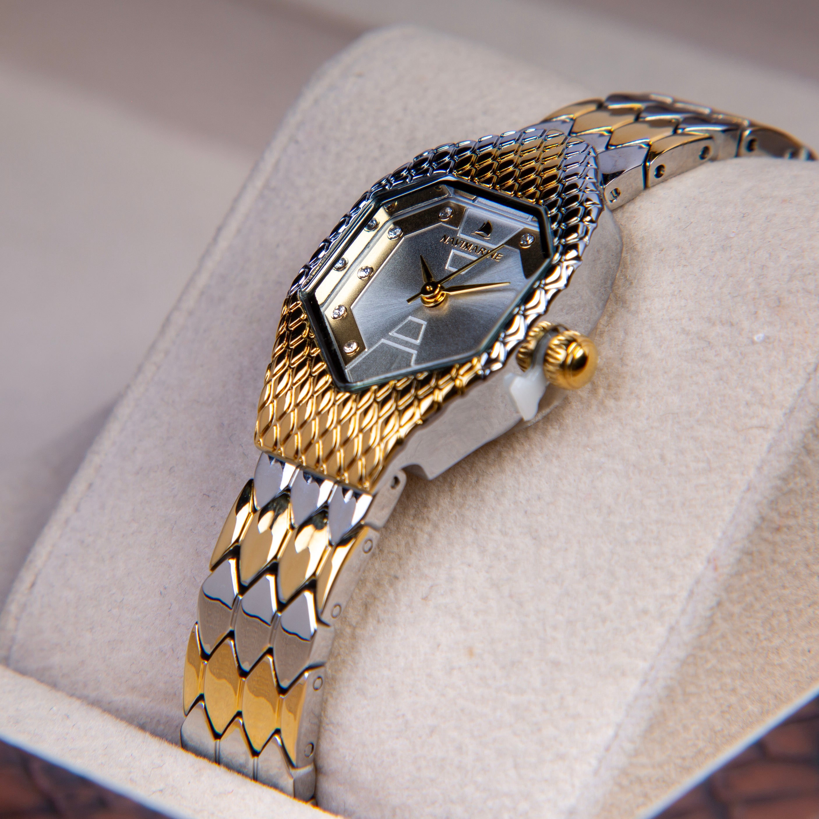 Gold and silver watch on a cushioned surface