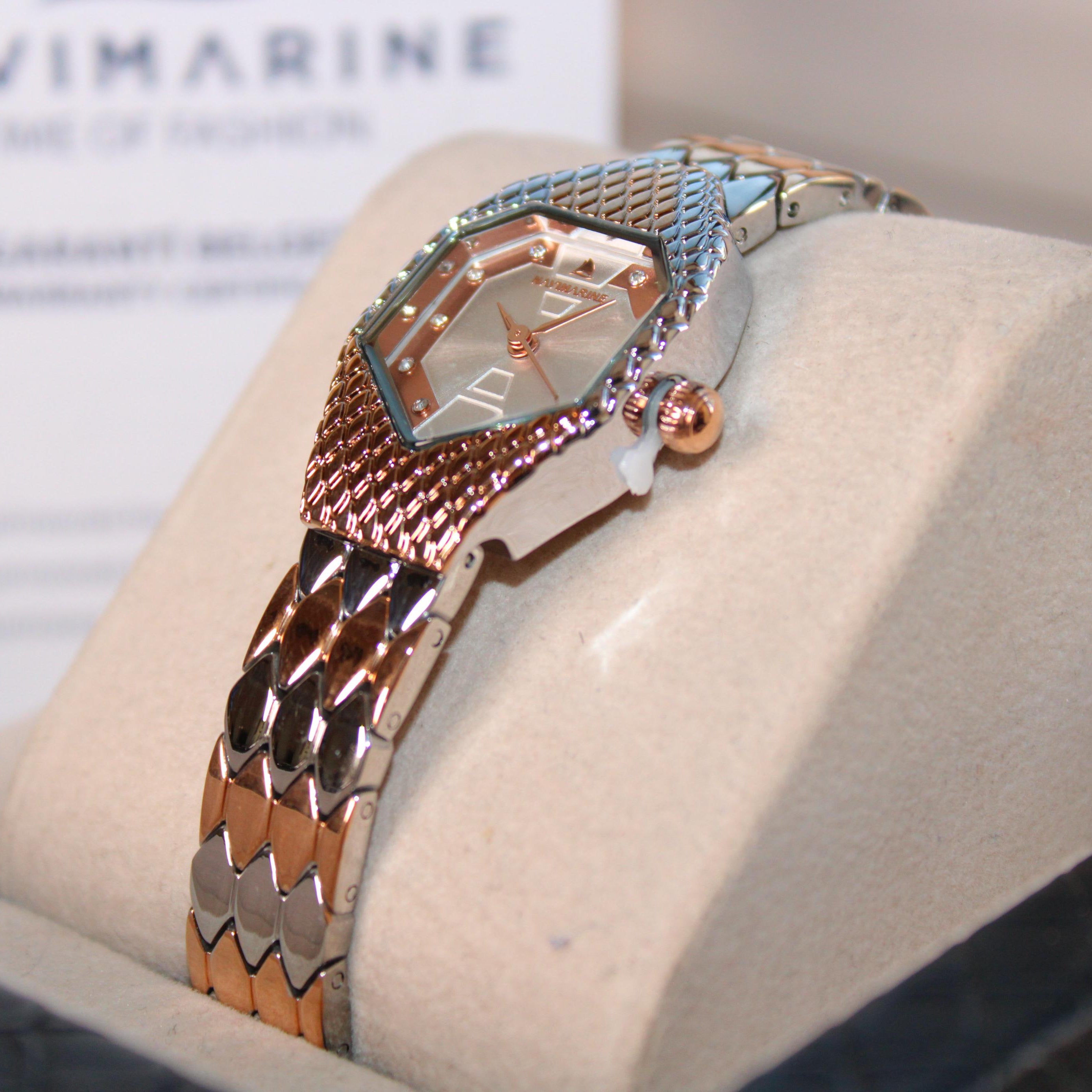 Luxury watch with rose gold and silver chain strap on a display stand, brand 'Navimagine' visible.