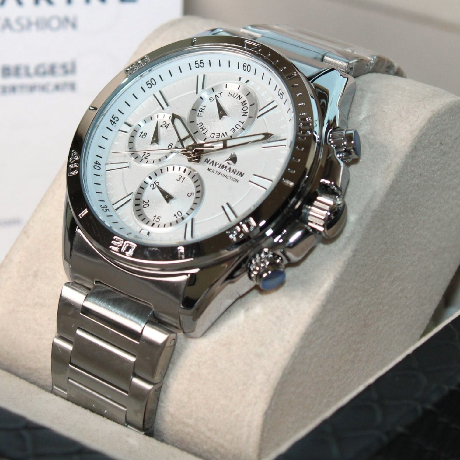Silver wristwatch with a white face on a light gray surface