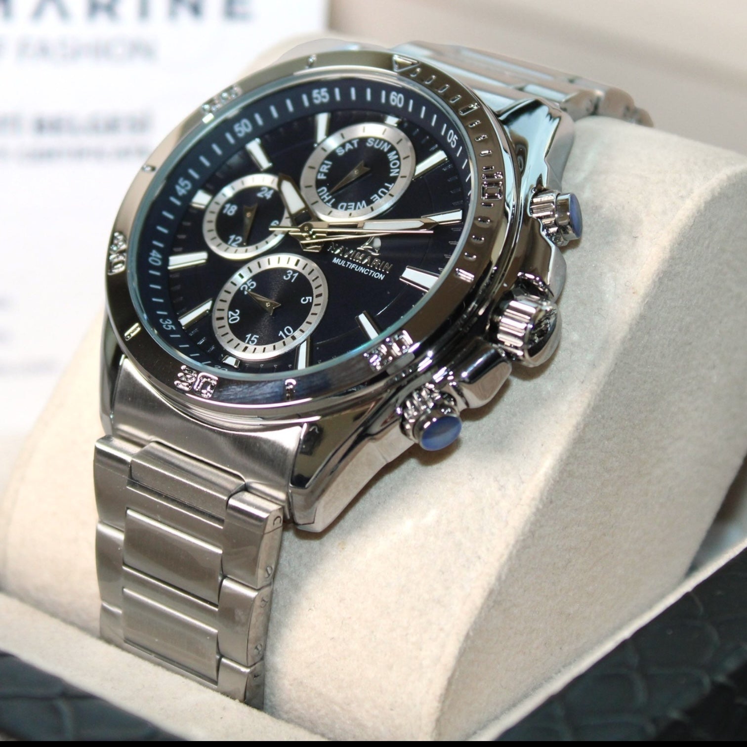 Silver watch with a black face on a white cushion