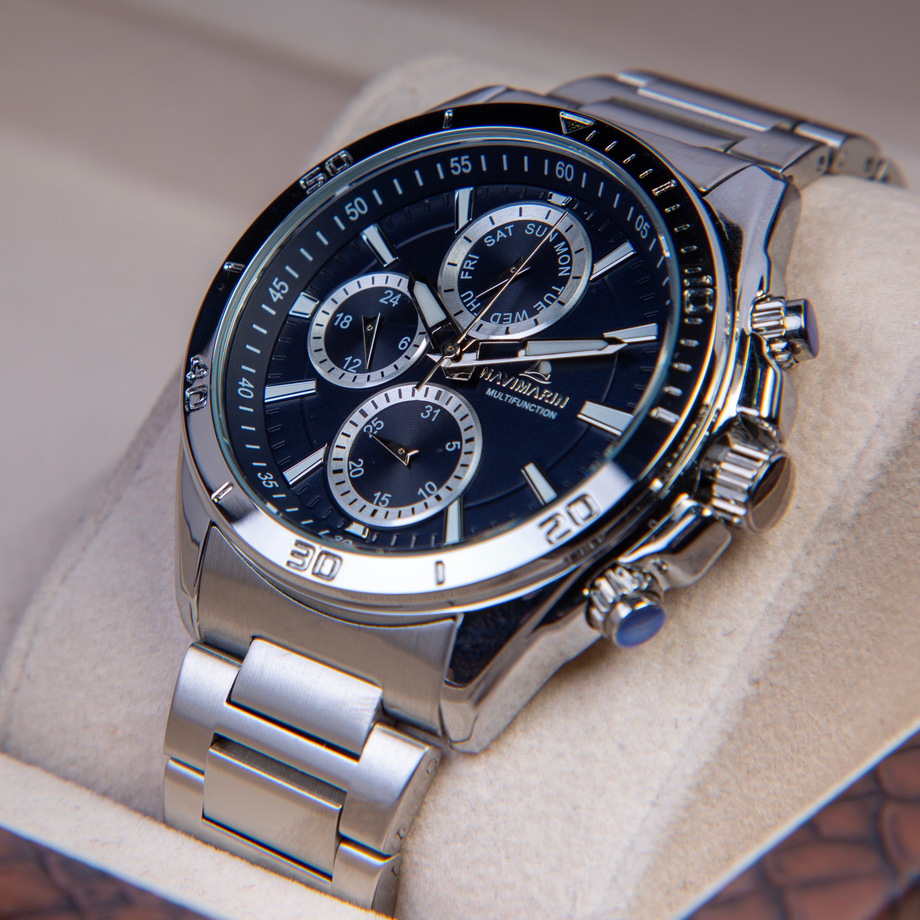Silver wristwatch with a black face on a beige cushion