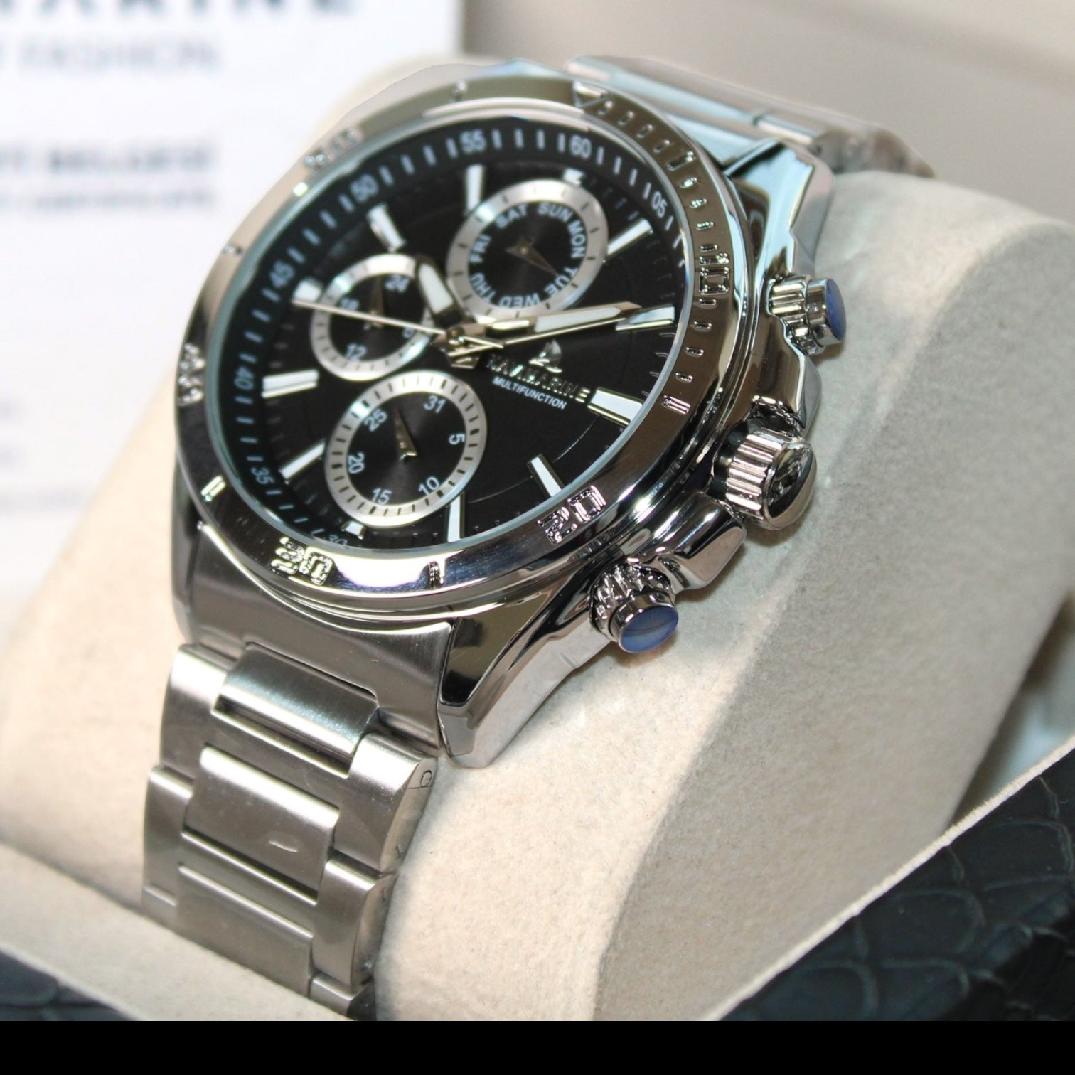 Silver watch with a black face on a white cushion