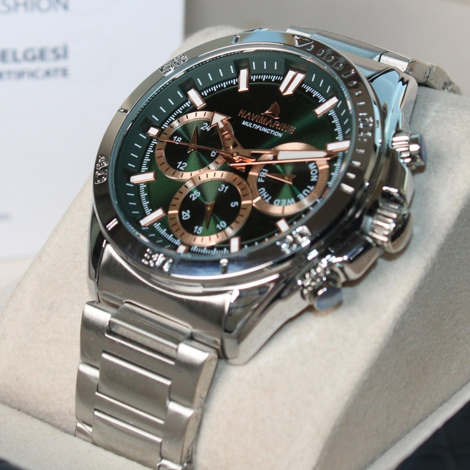 Silver watch with a green face on a light gray surface