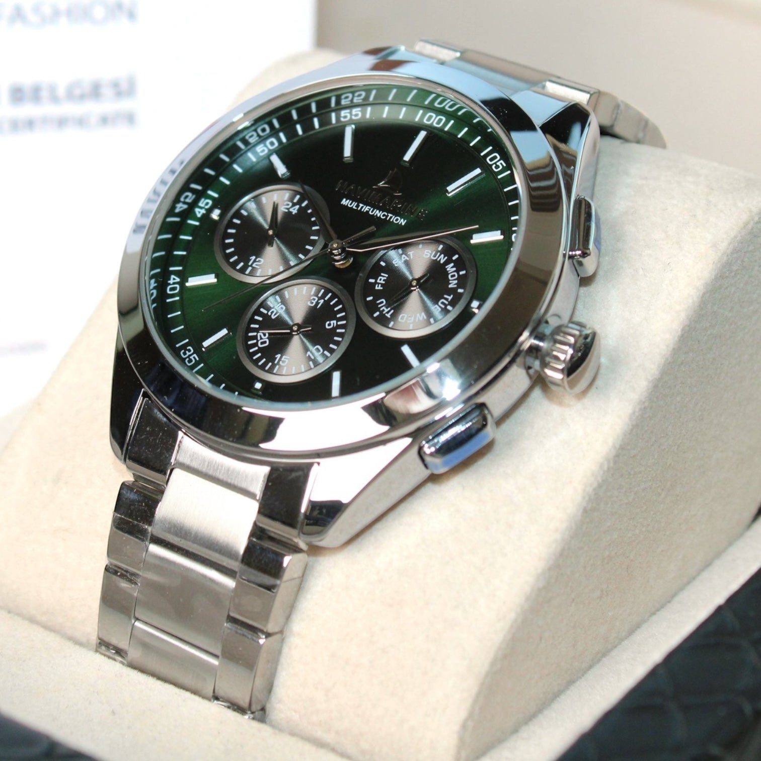 Silver watch with a green dial on a white cushion