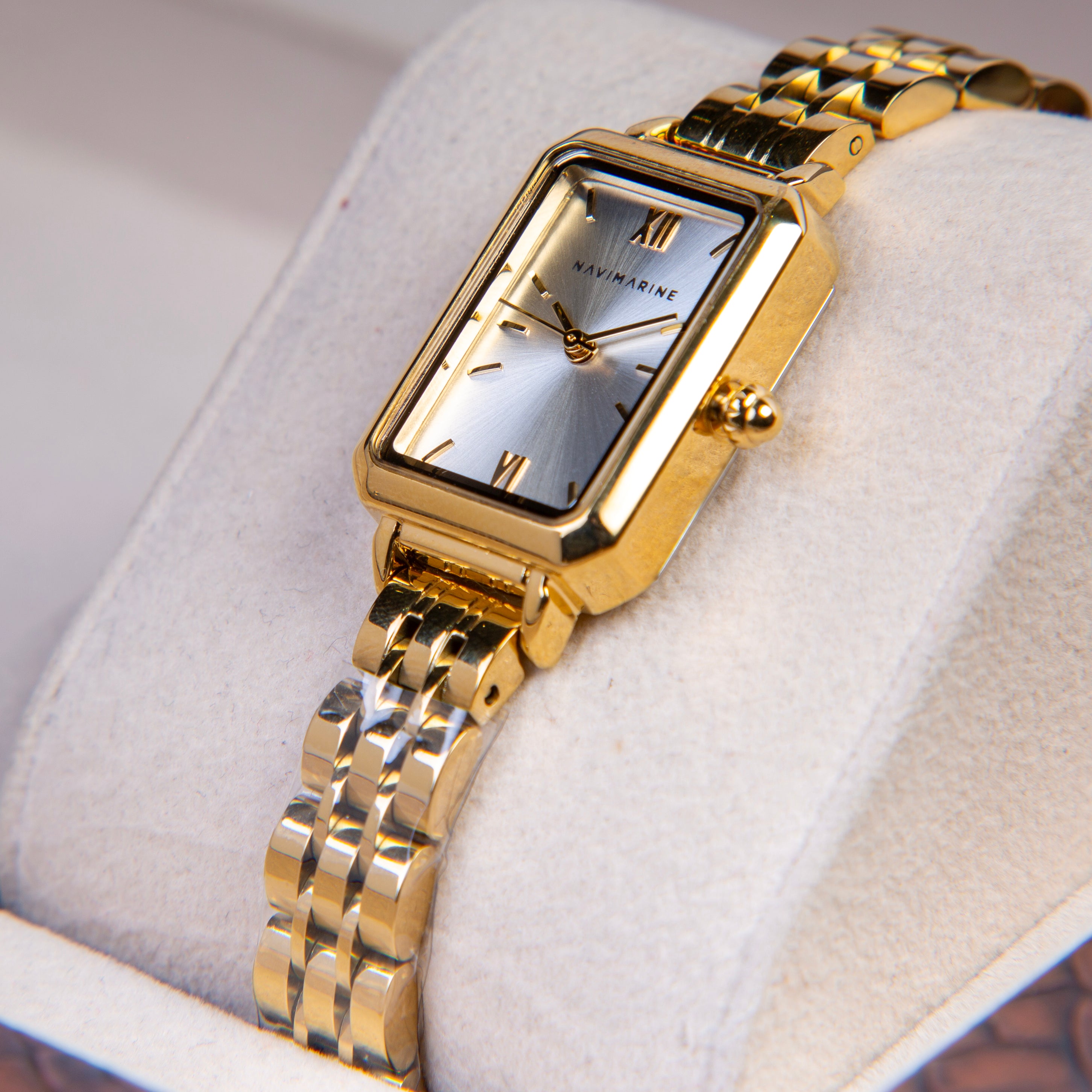 Gold wristwatch with a silver face on a white cushion