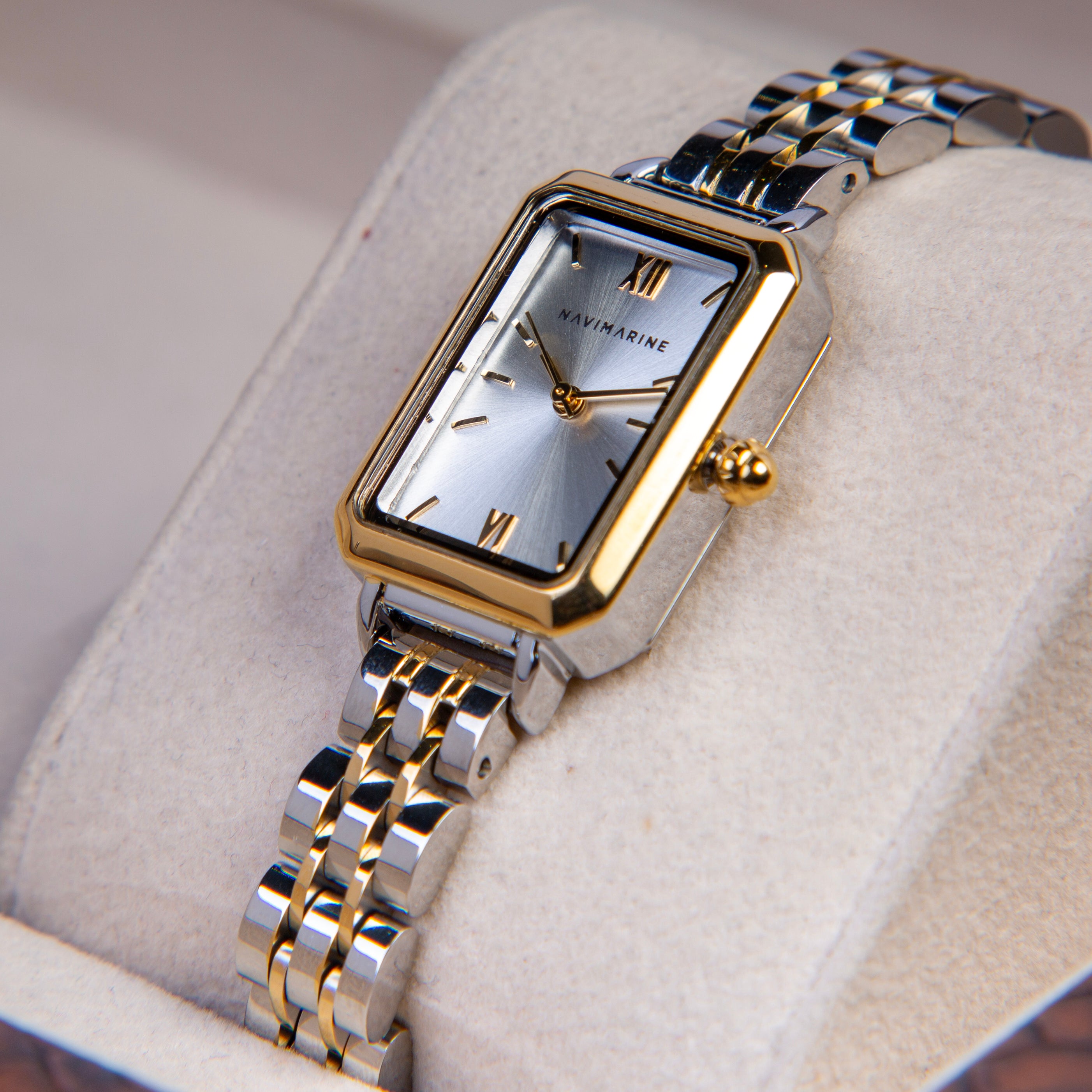 Silver and gold watch with a white face on a light gray background
