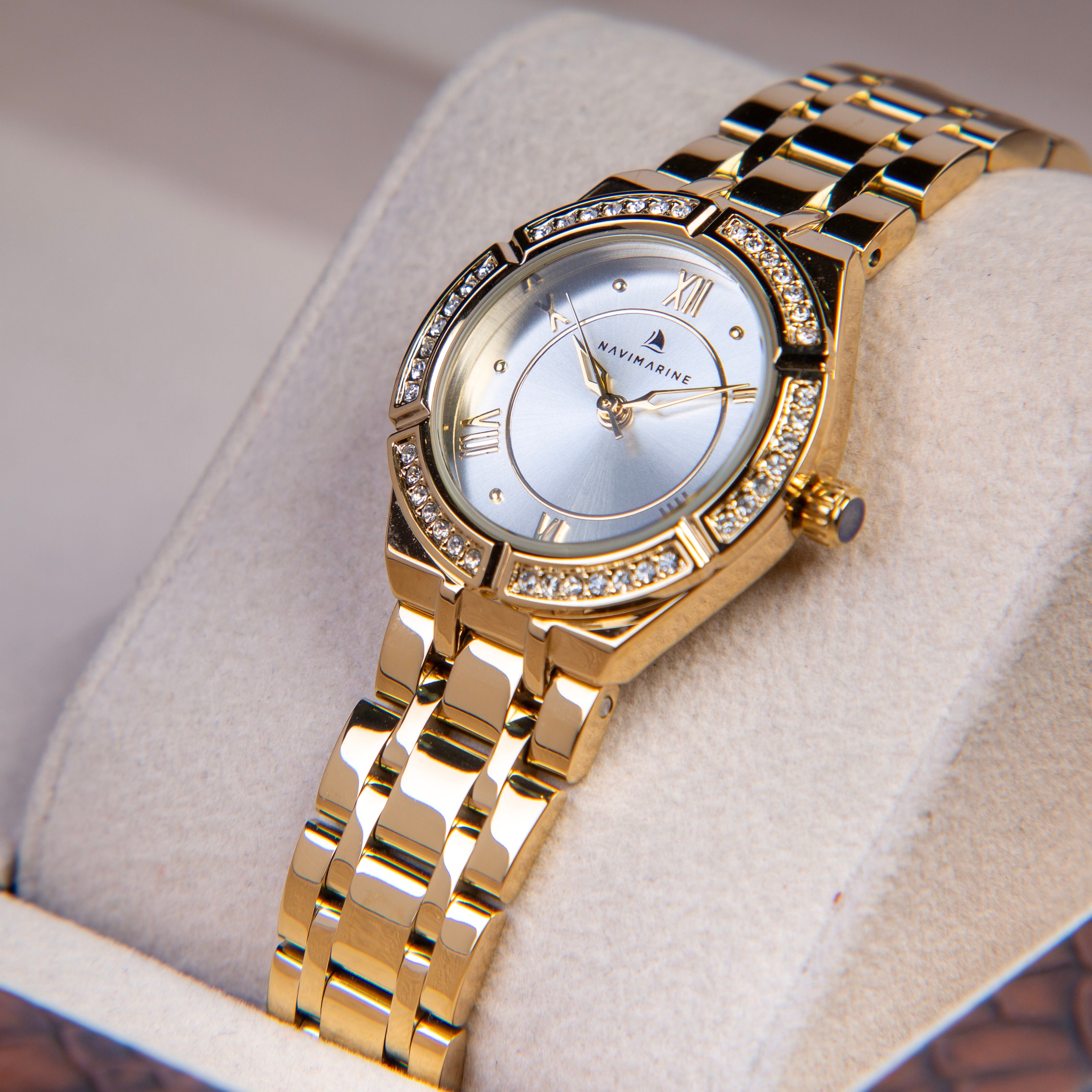 Gold wristwatch with diamond accents on a soft surface