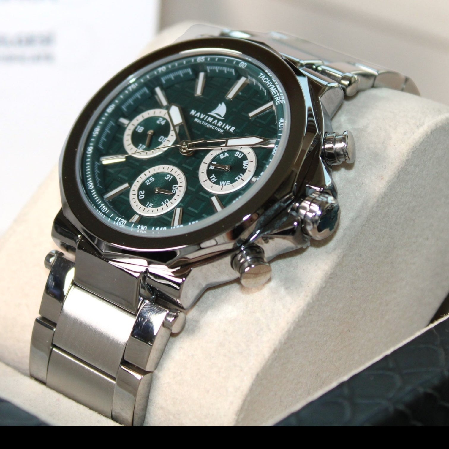 Silver wristwatch with a green dial on a white cushion
