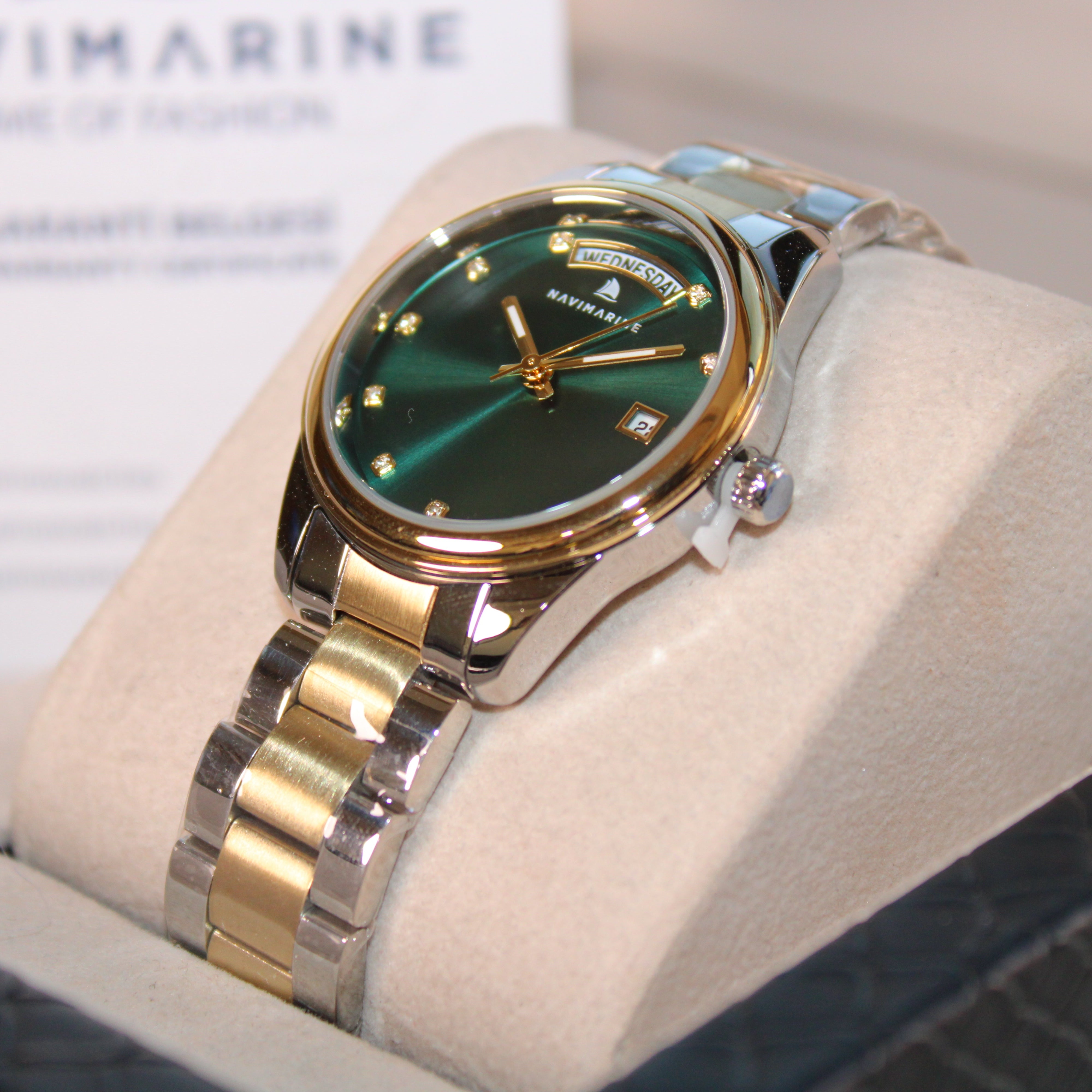Navimagine watch with green face and gold accents on a display stand.