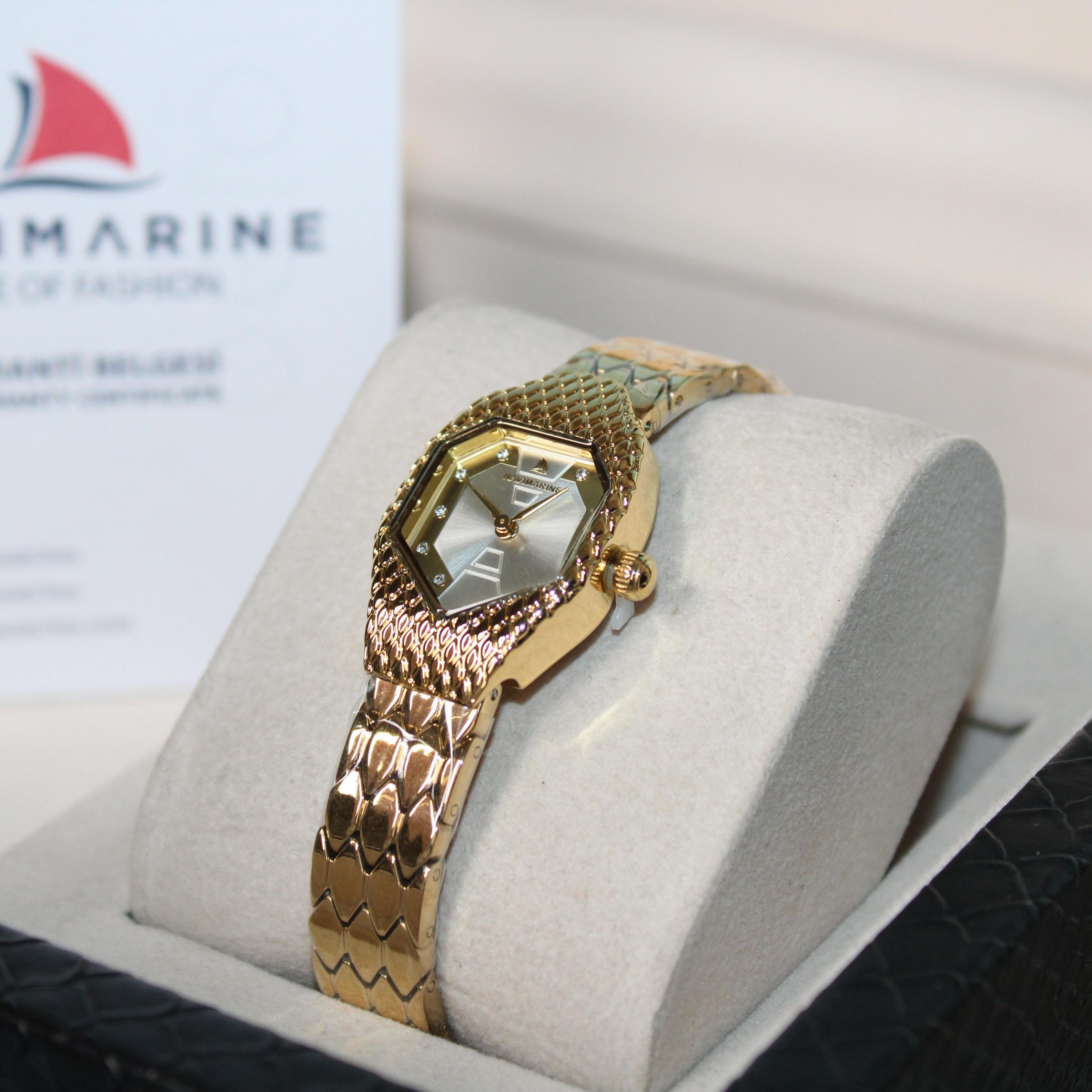 Gold wristwatch on a display stand with Navimarine branding in the background