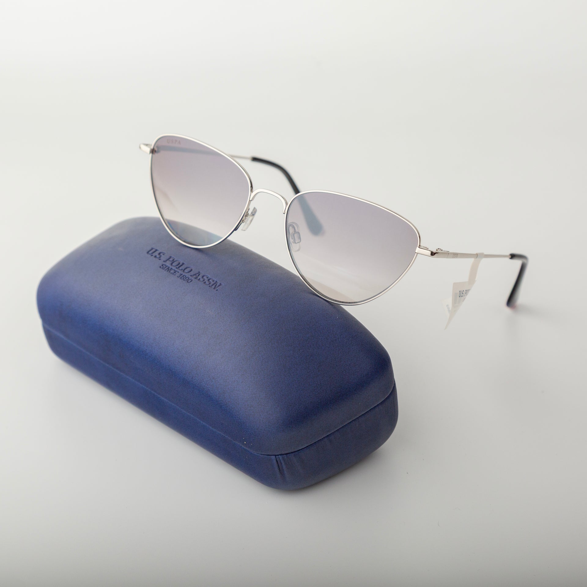 Cat-eye sunglasses with a blue case on a light gray background