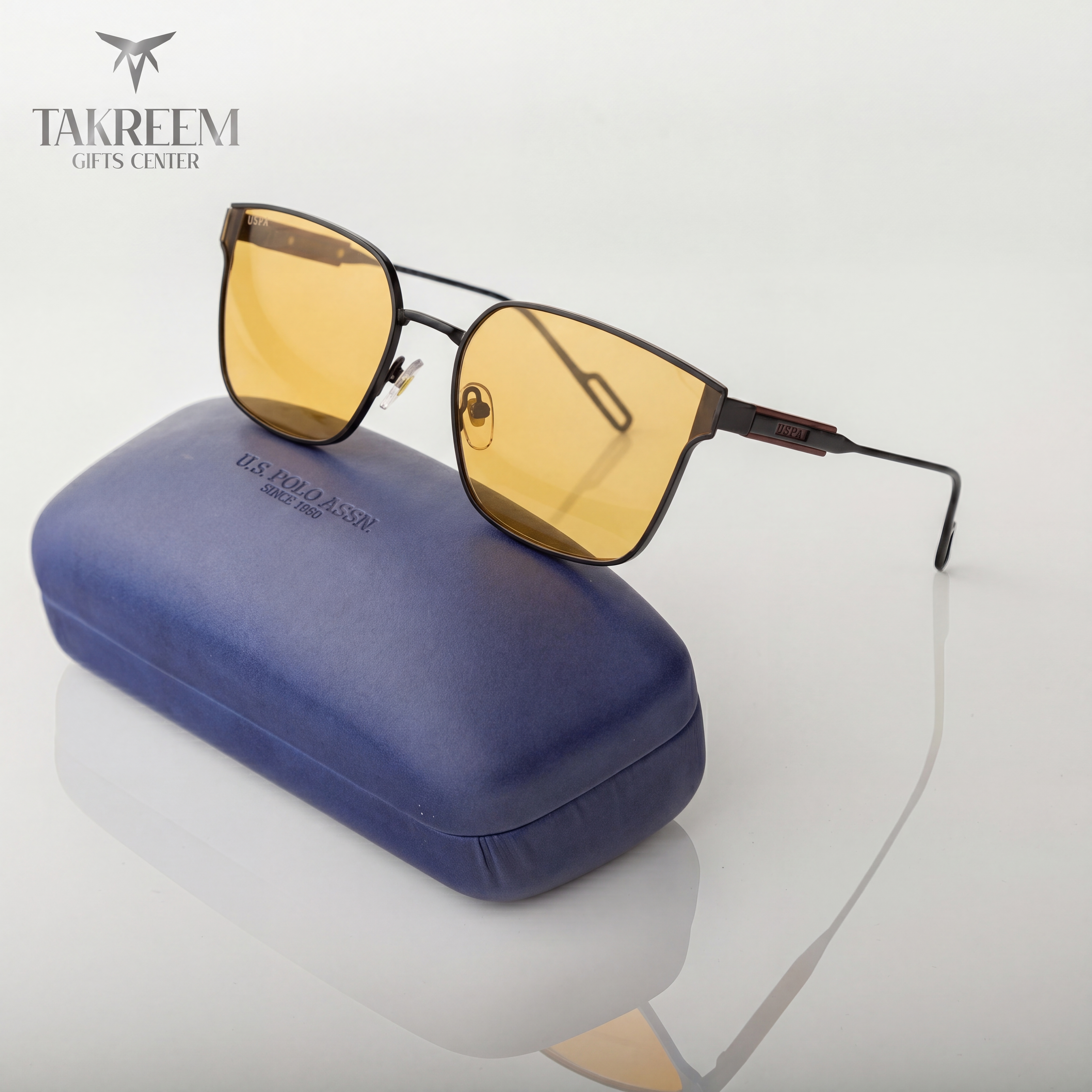 Sunglasses with yellow lenses on a blue case, brand 'Takreem' visible
