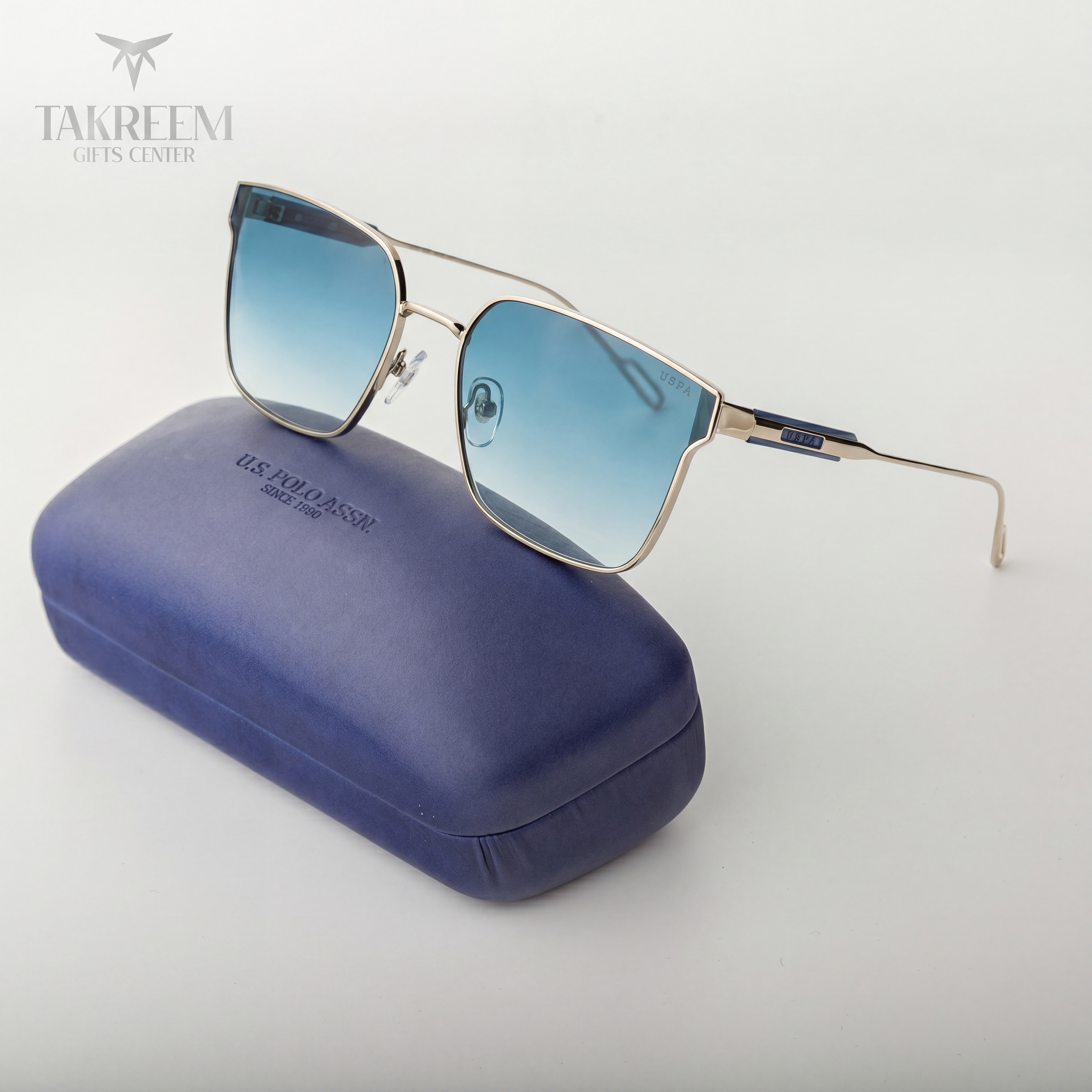 Sunglasses with blue gradient lenses on a blue case, brand 'Takreem' visible.