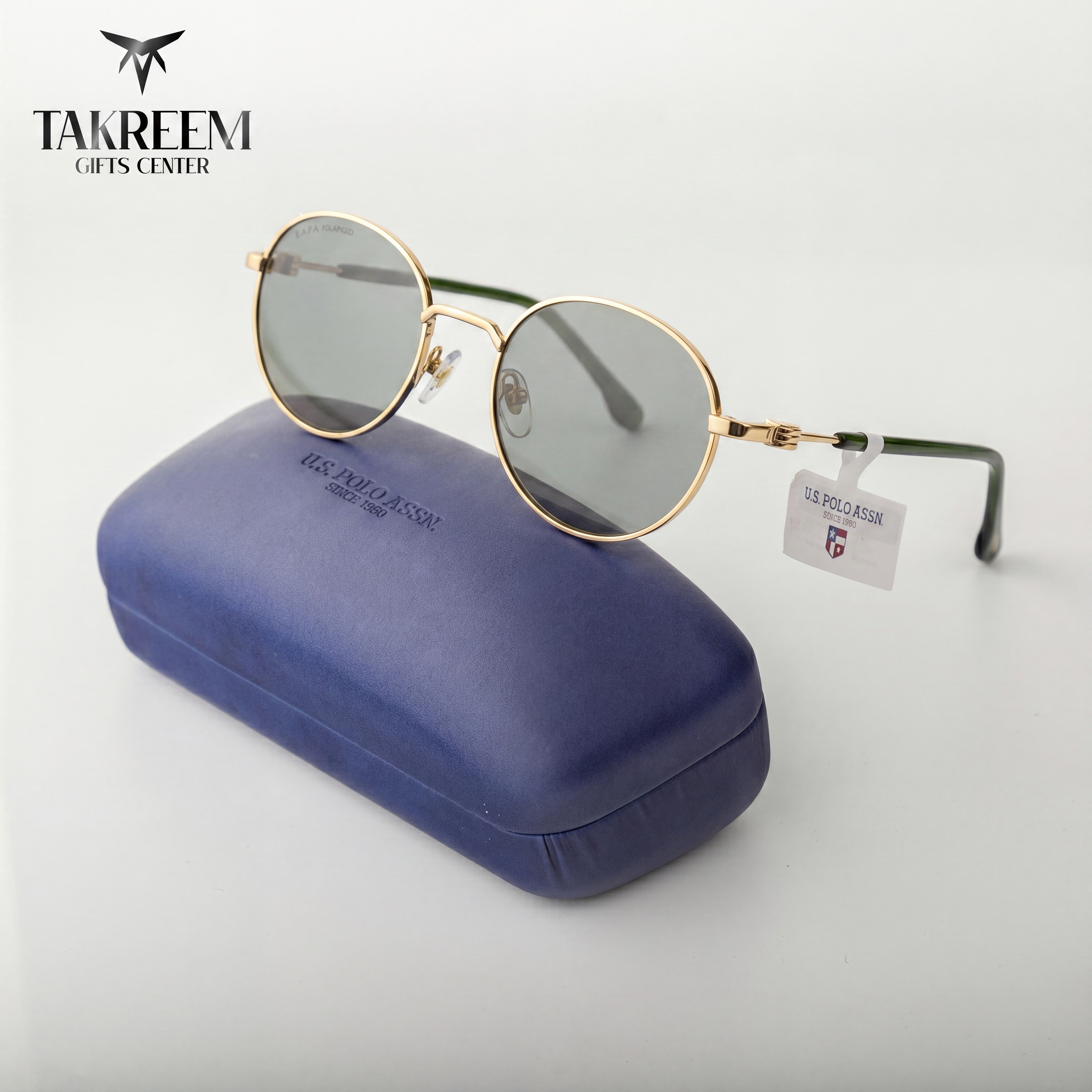 Gold-framed sunglasses with a blue case on a white background, featuring the Takreem Gifts Center logo.