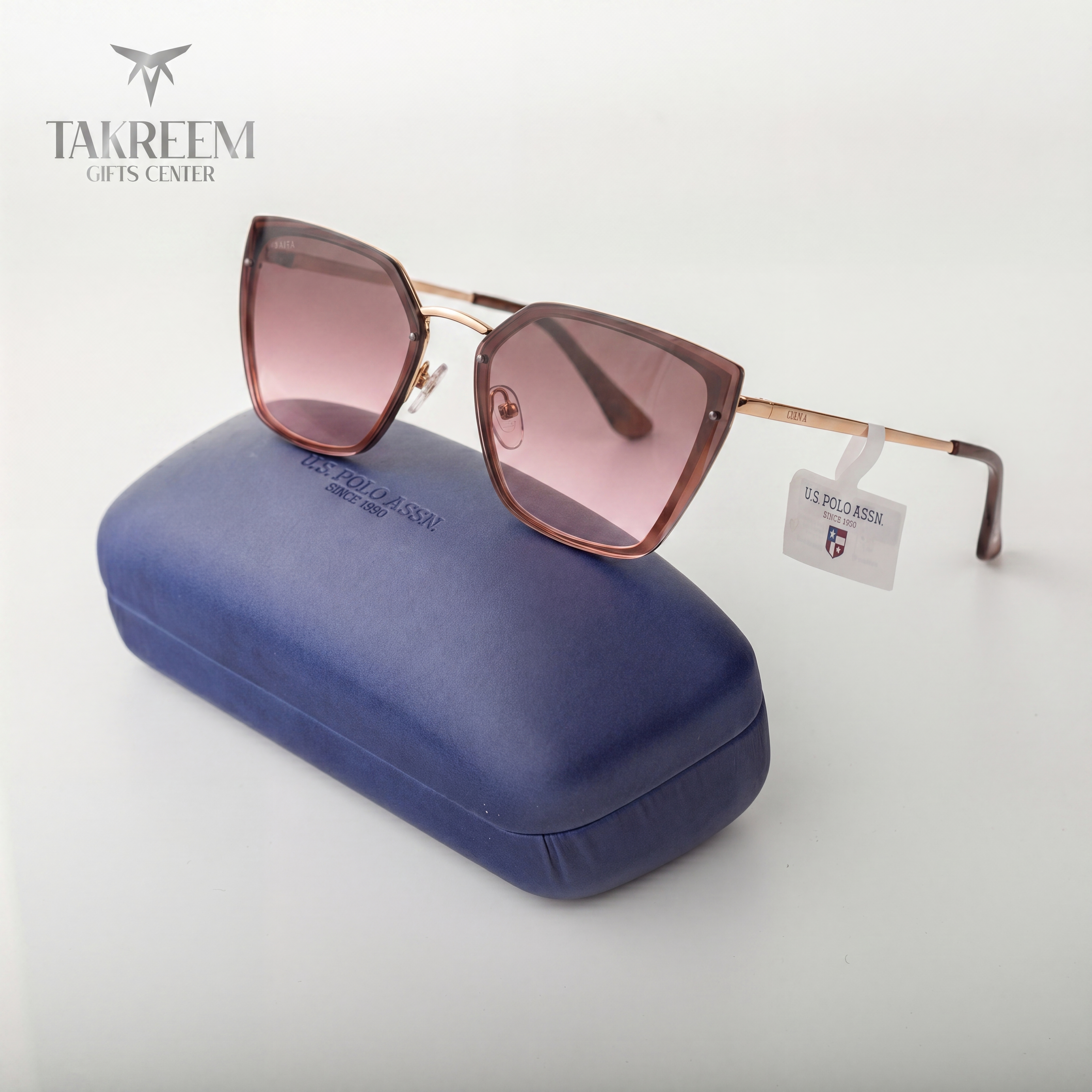 Sunglasses with pink lenses on a blue case, brand 'Takreem' visible.