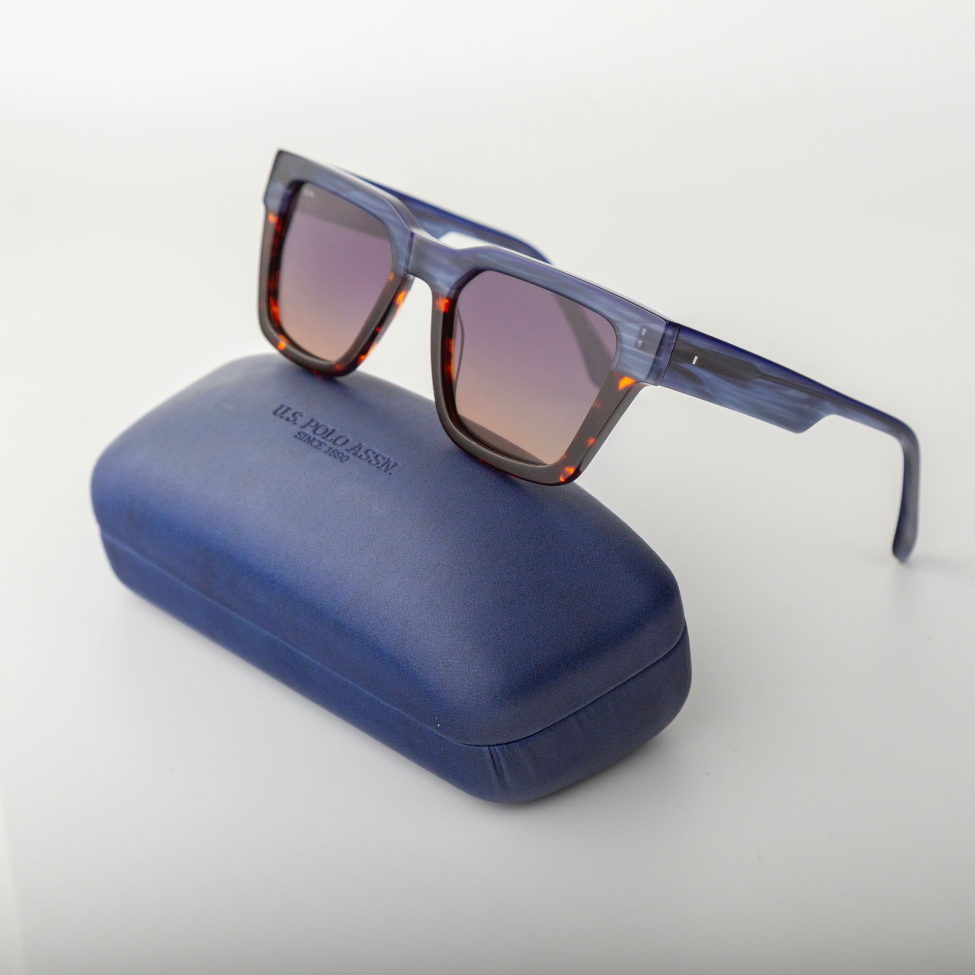 Blue sunglasses with tortoiseshell accents on a blue case against a white background