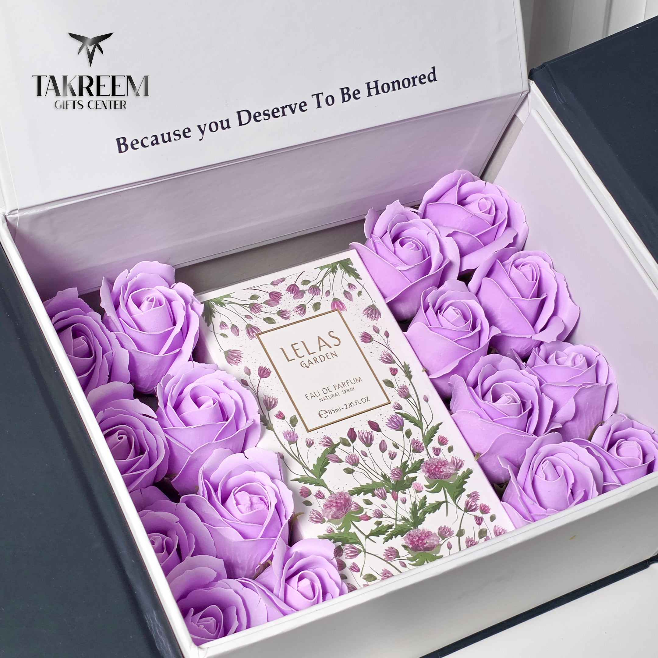 A gift box filled with lavender-colored preserved roses and a central card reading 'Lelas Garden Eau De Parfum'. The open box lid shows the Takreem Gifts Center branding.