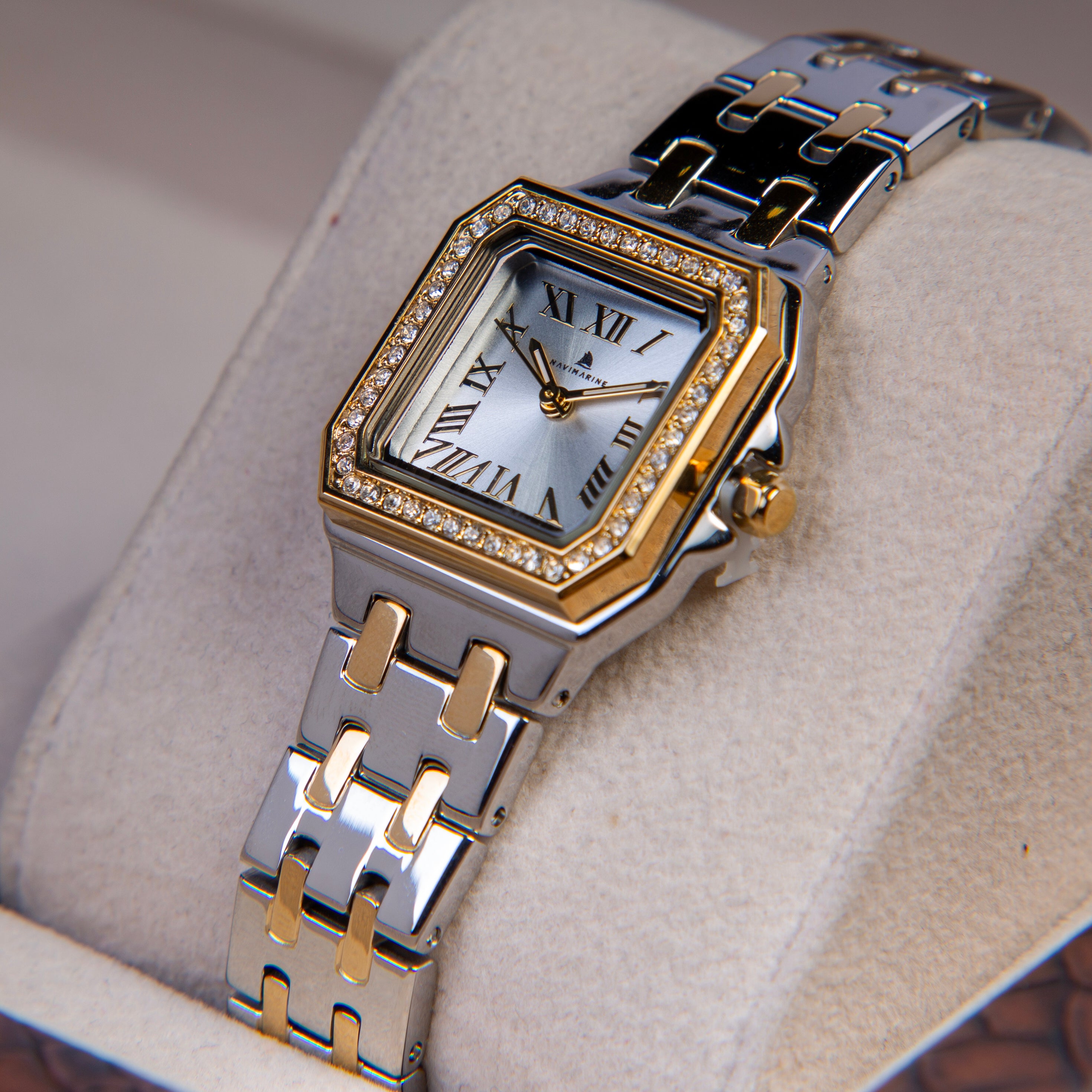 Silver and gold watch with diamond-studded face on a textured surface
