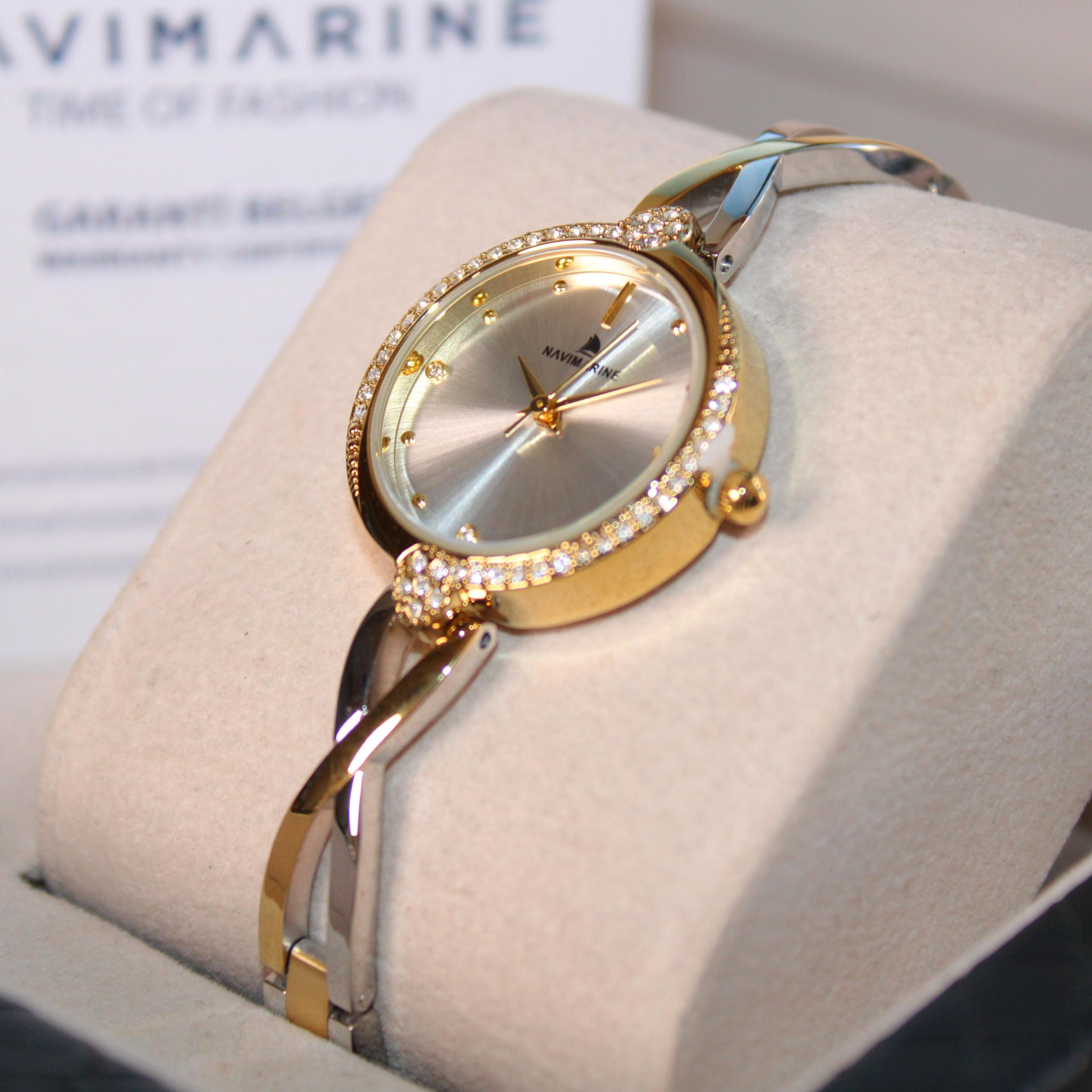 Gold and silver watch on a white cushion with a blurred background