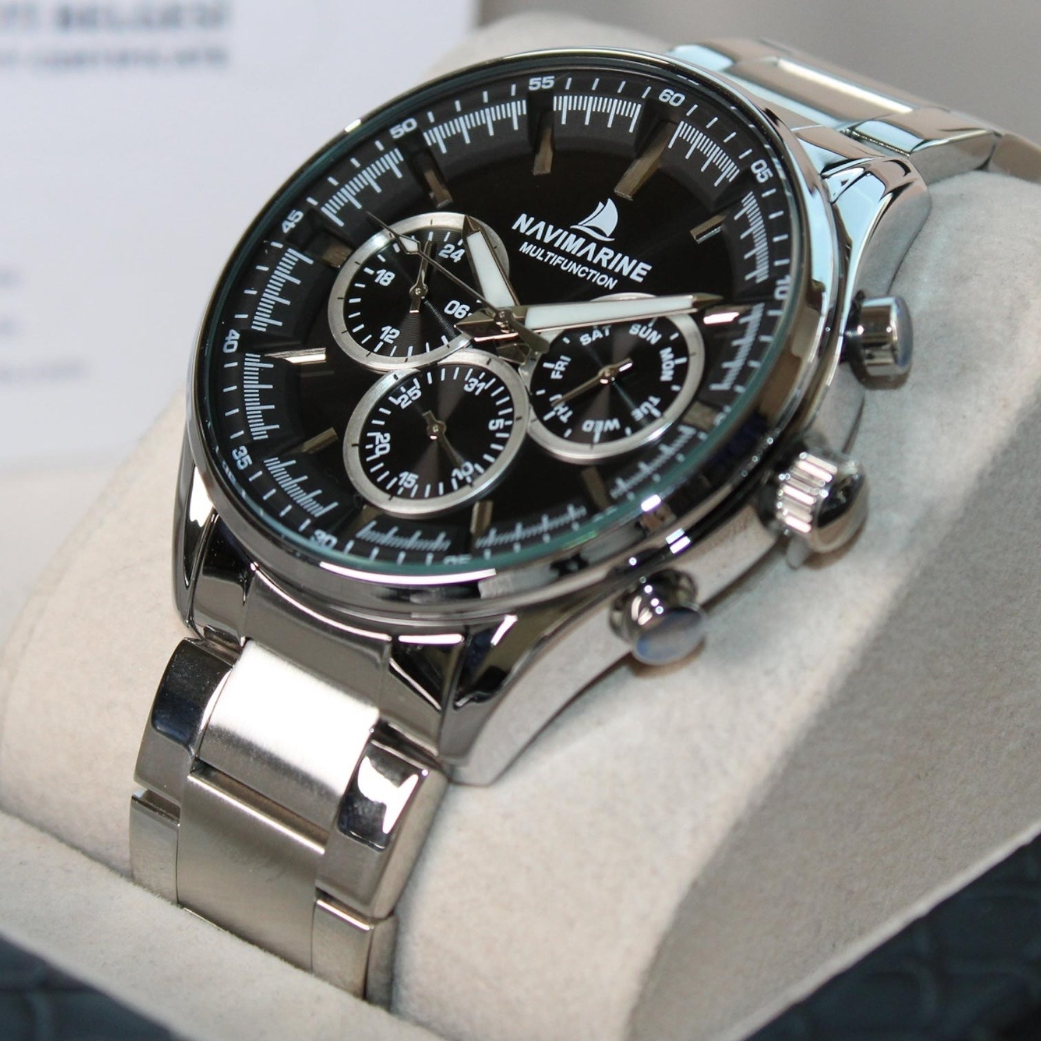 Navimagine watch with black face and silver band on a white cushion