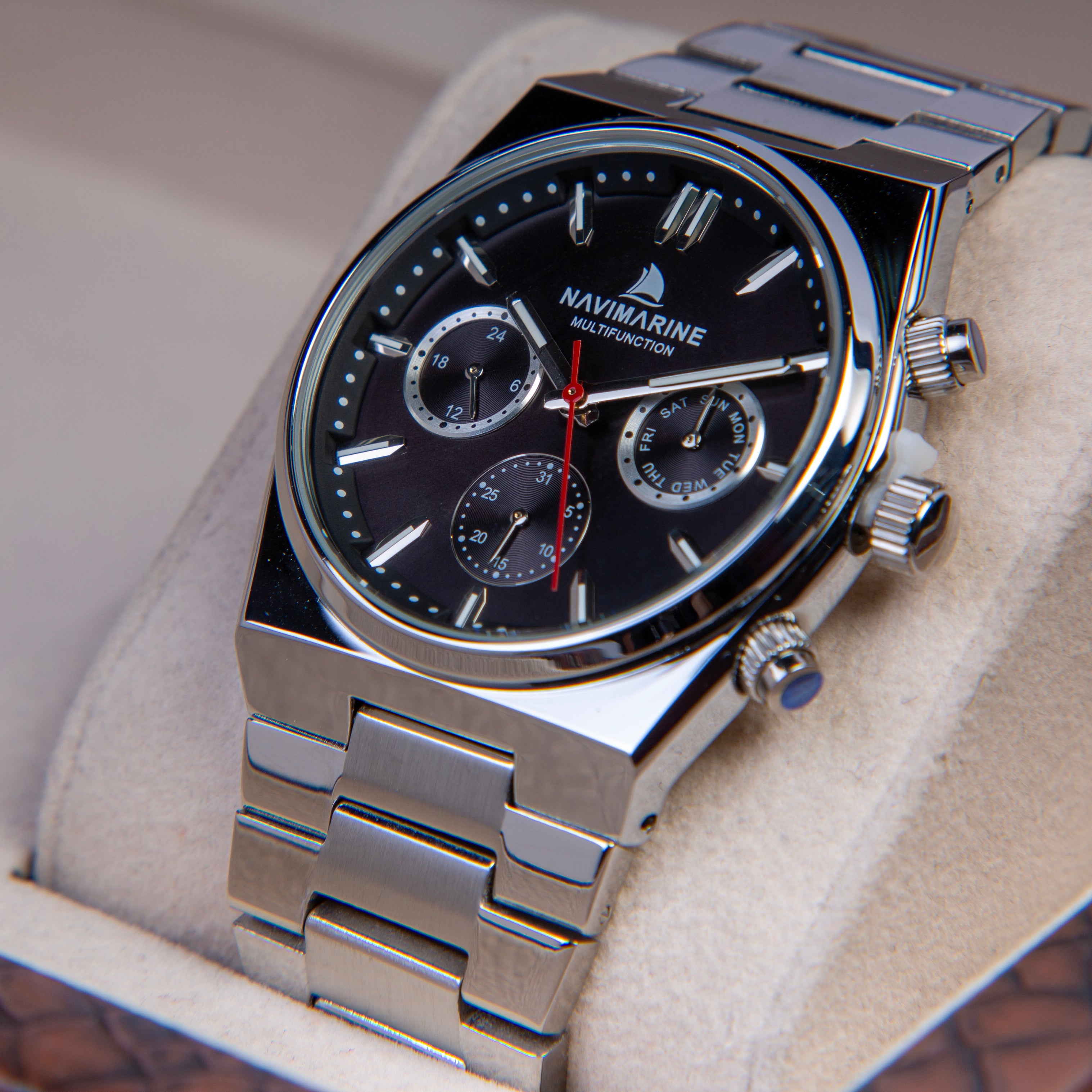 Silver wristwatch with black dial on a beige cushion