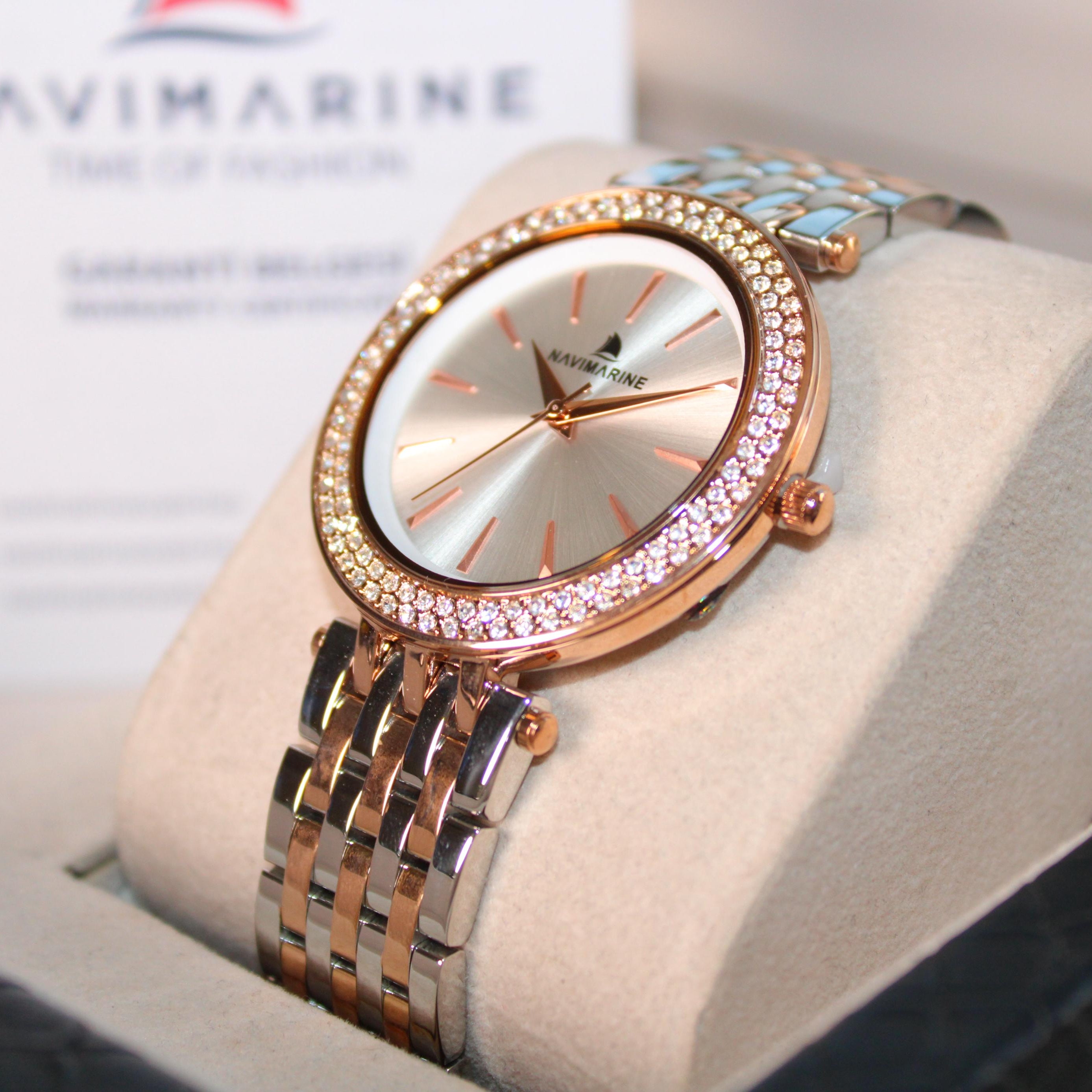 Luxury watch with rose gold and silver band on a white cushion, brand 'NaviMarine' visible.