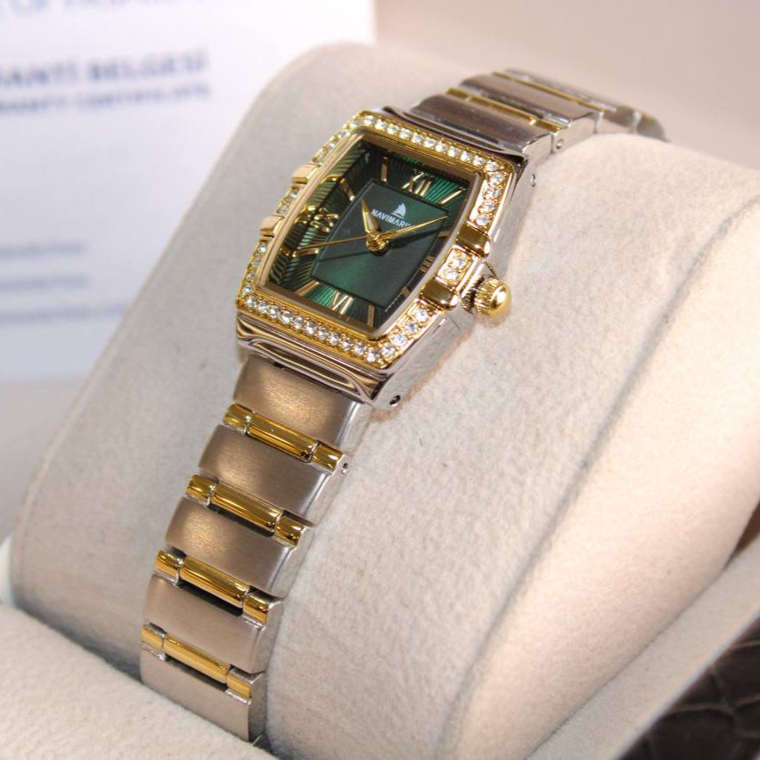 Luxury watch with green face and gold accents on a white cushion