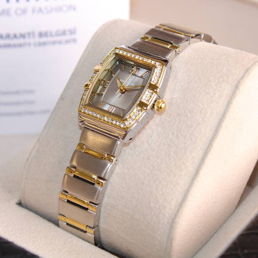 Gold and silver watch on a white cushion with a blurred background