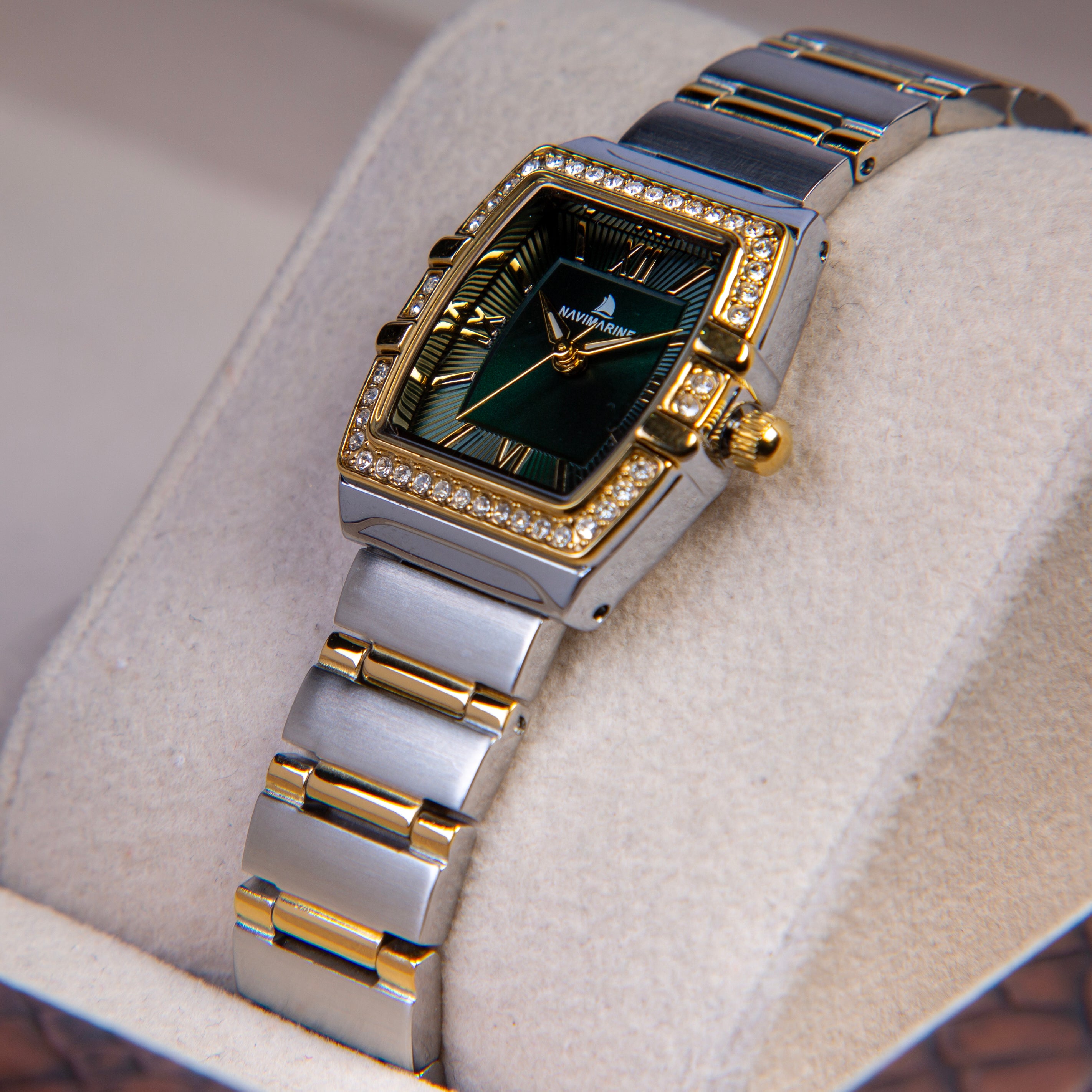 Luxury watch with green face and gold accents on a soft surface