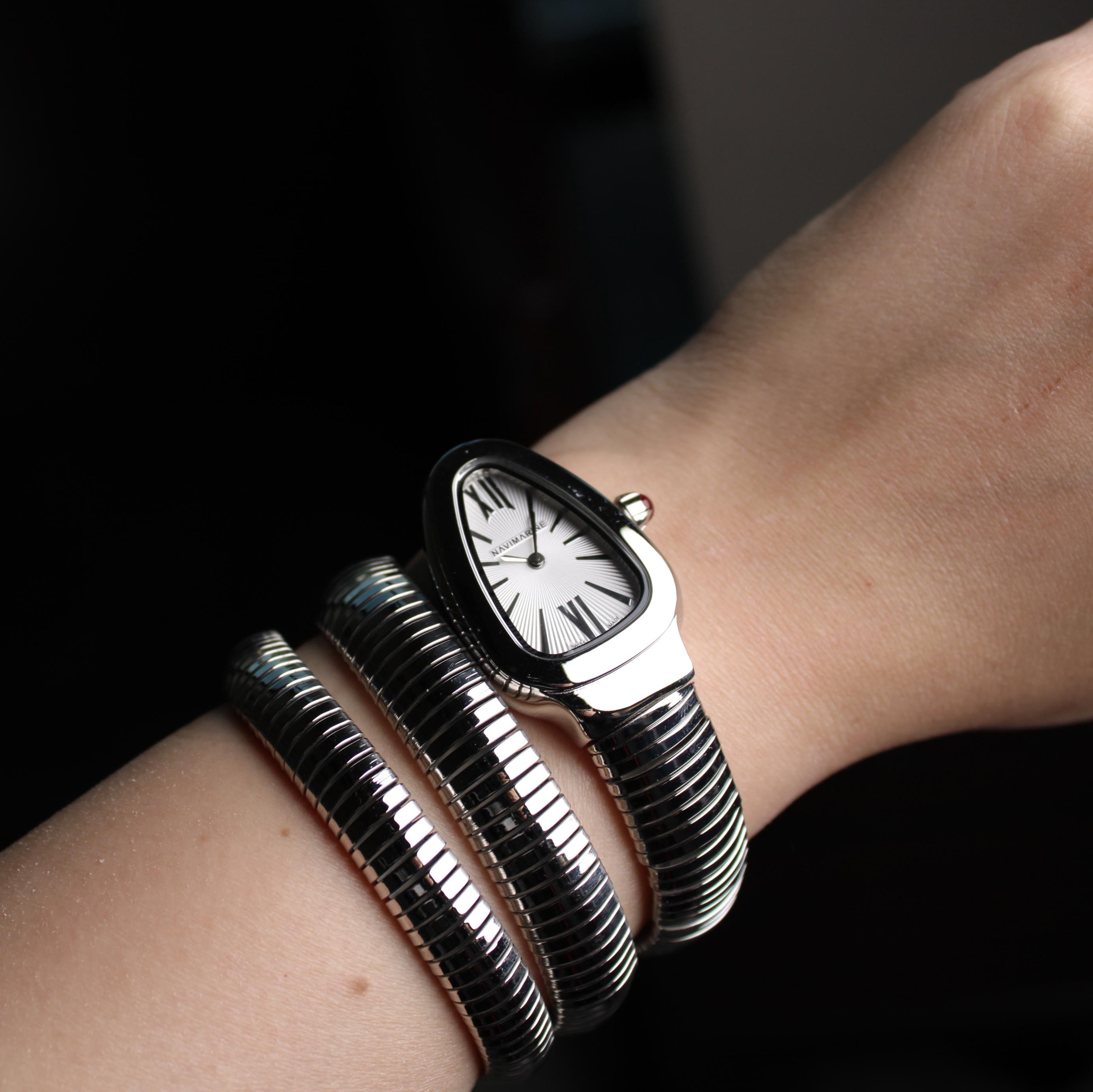 Close-up of a wrist wearing multiple bracelets with a watch face design on a dark background