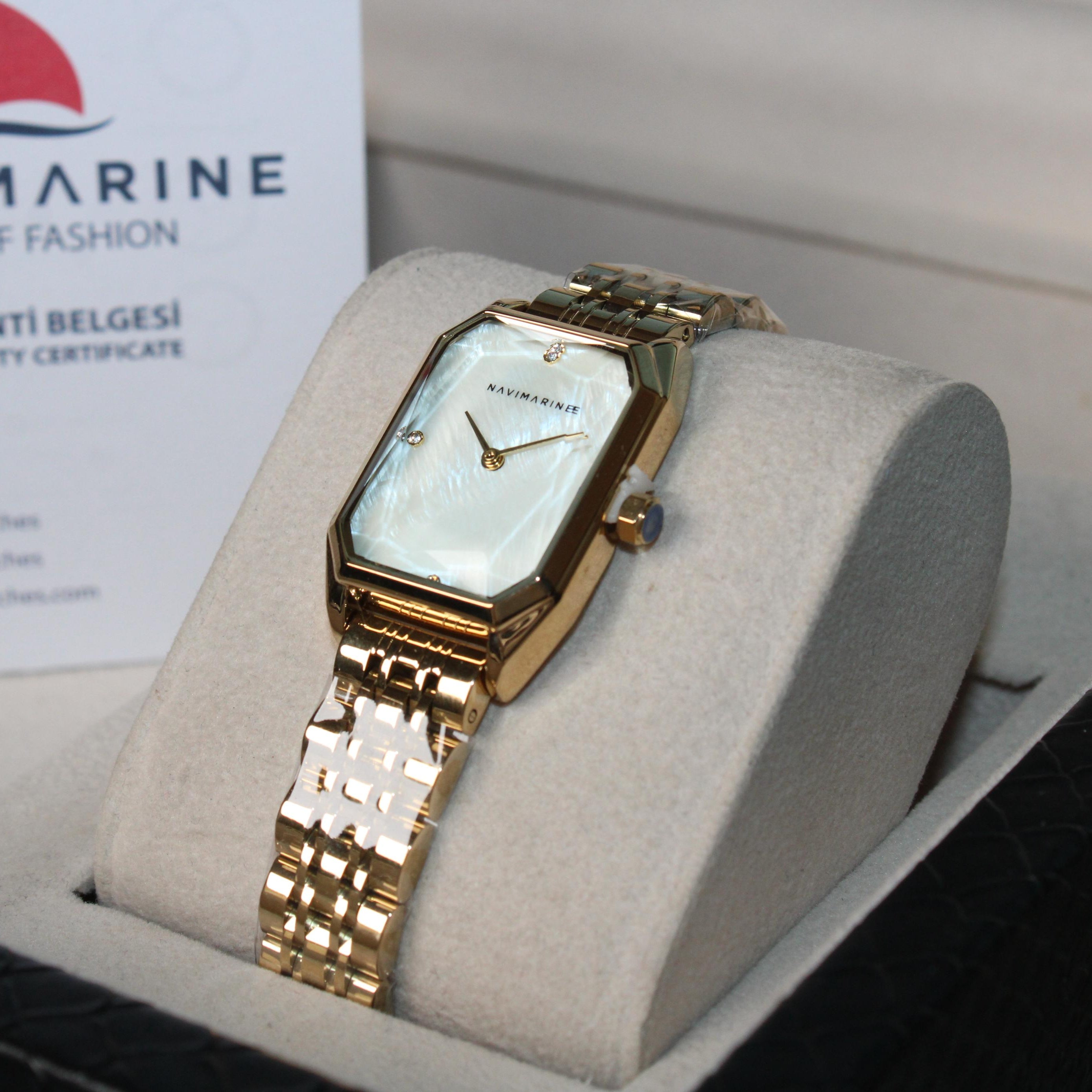 Gold wristwatch on a display stand with Navimarine branding in the background