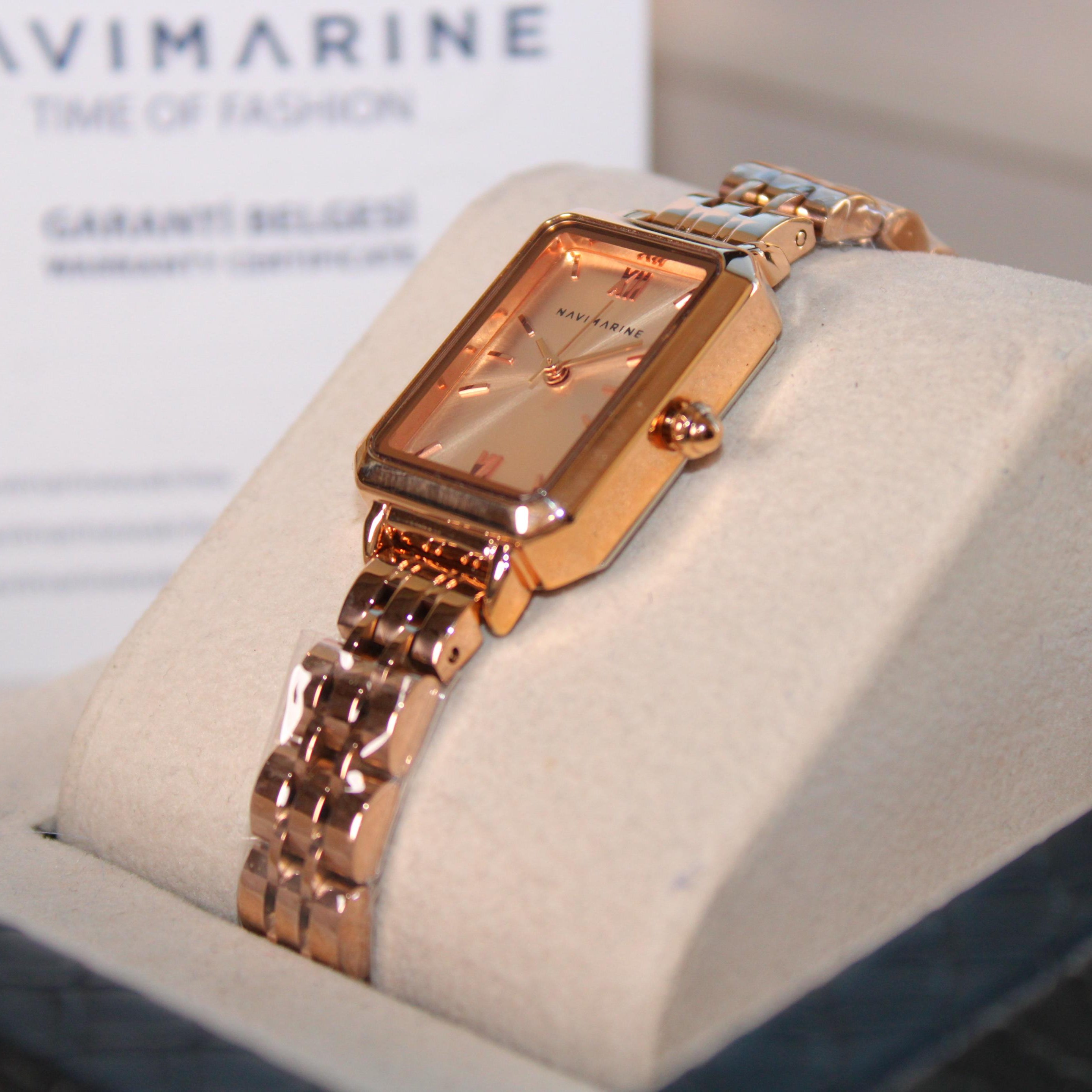 Rose gold watch on display with a visible brand name in the background