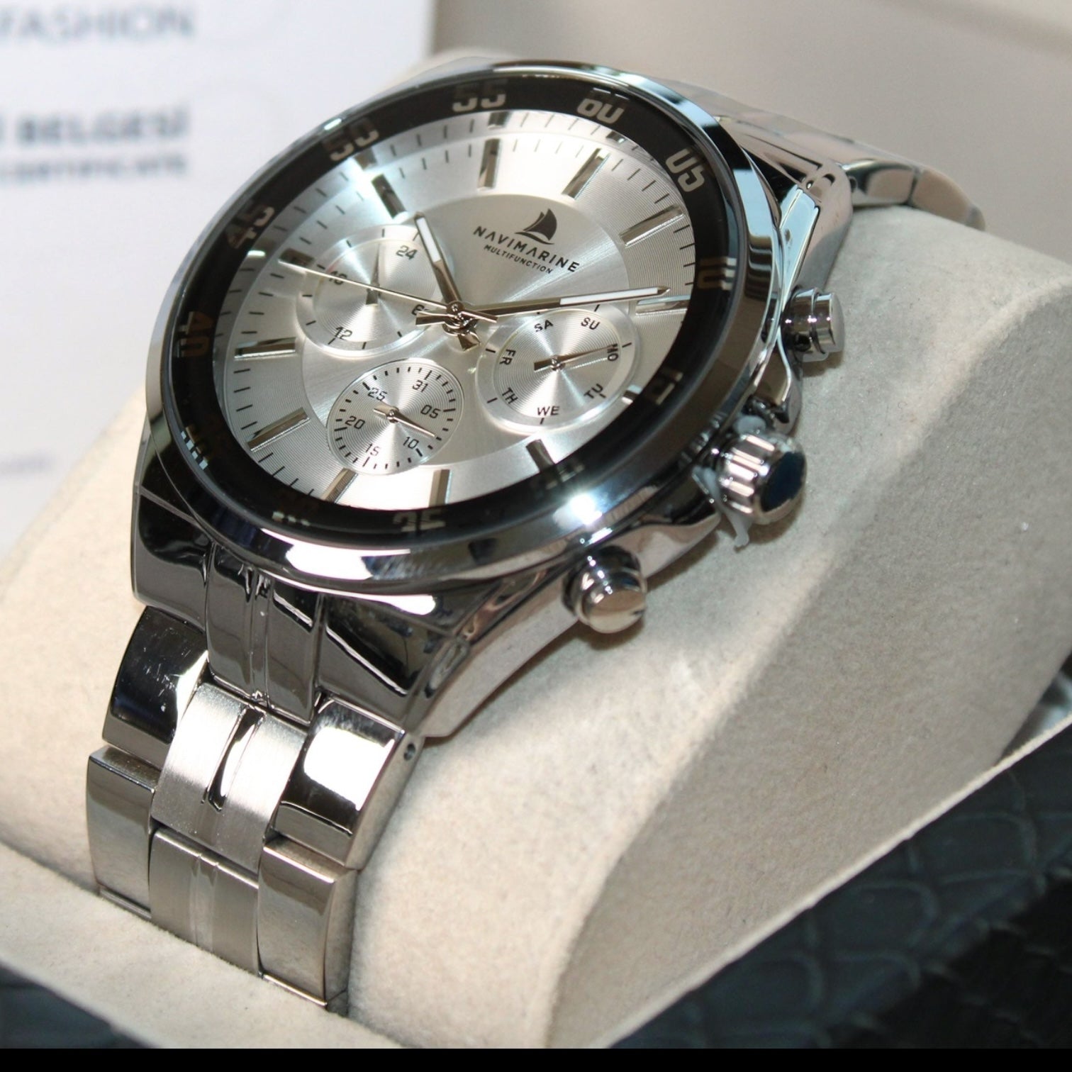Silver wristwatch with detailed face on a white cushion