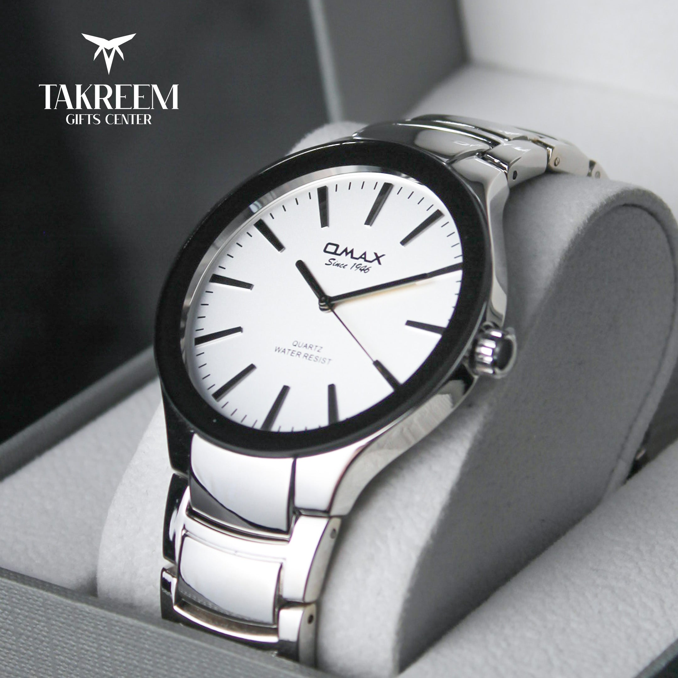 Silver watch with white face on a gray cushion, brand 'Takreem' visible