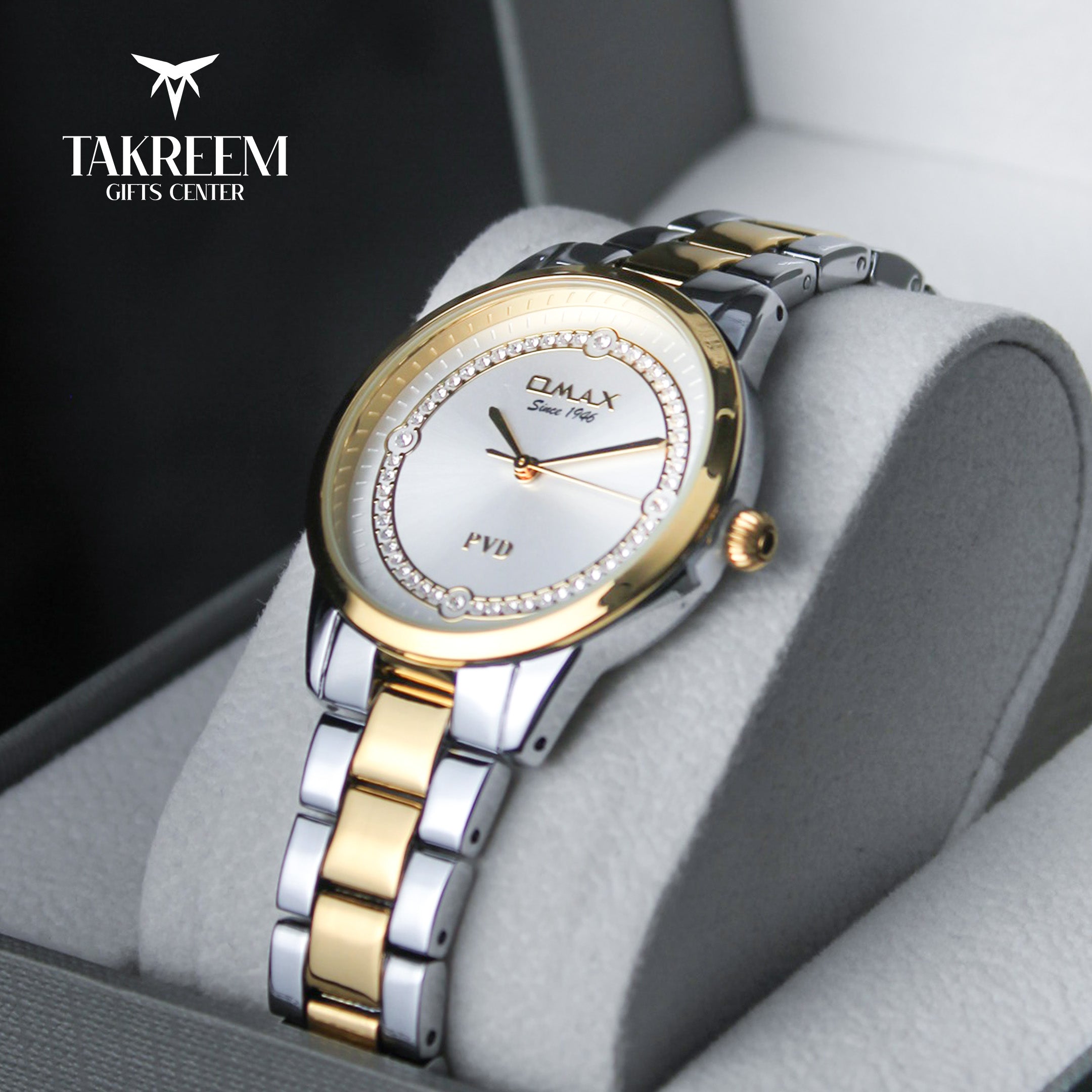 Two-tone watch with silver and gold band on a gray cushion, brand 'Takreem' visible.